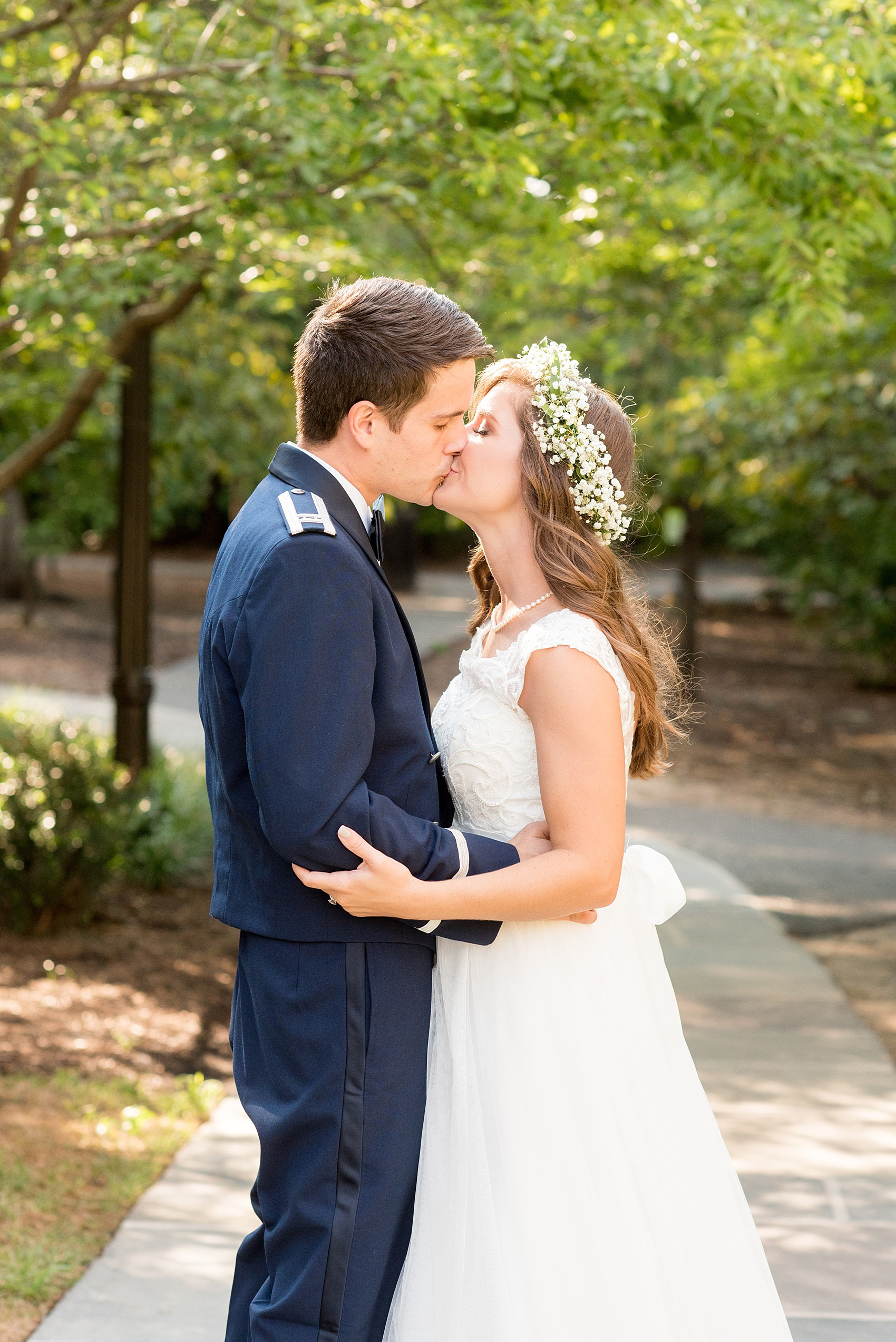 Mikkel Paige Photography photo of a Duke Chapel wedding in Durham, North Carolina. The bride and groom kiss in her lace cap gown and his navy blue Air Force uniform.