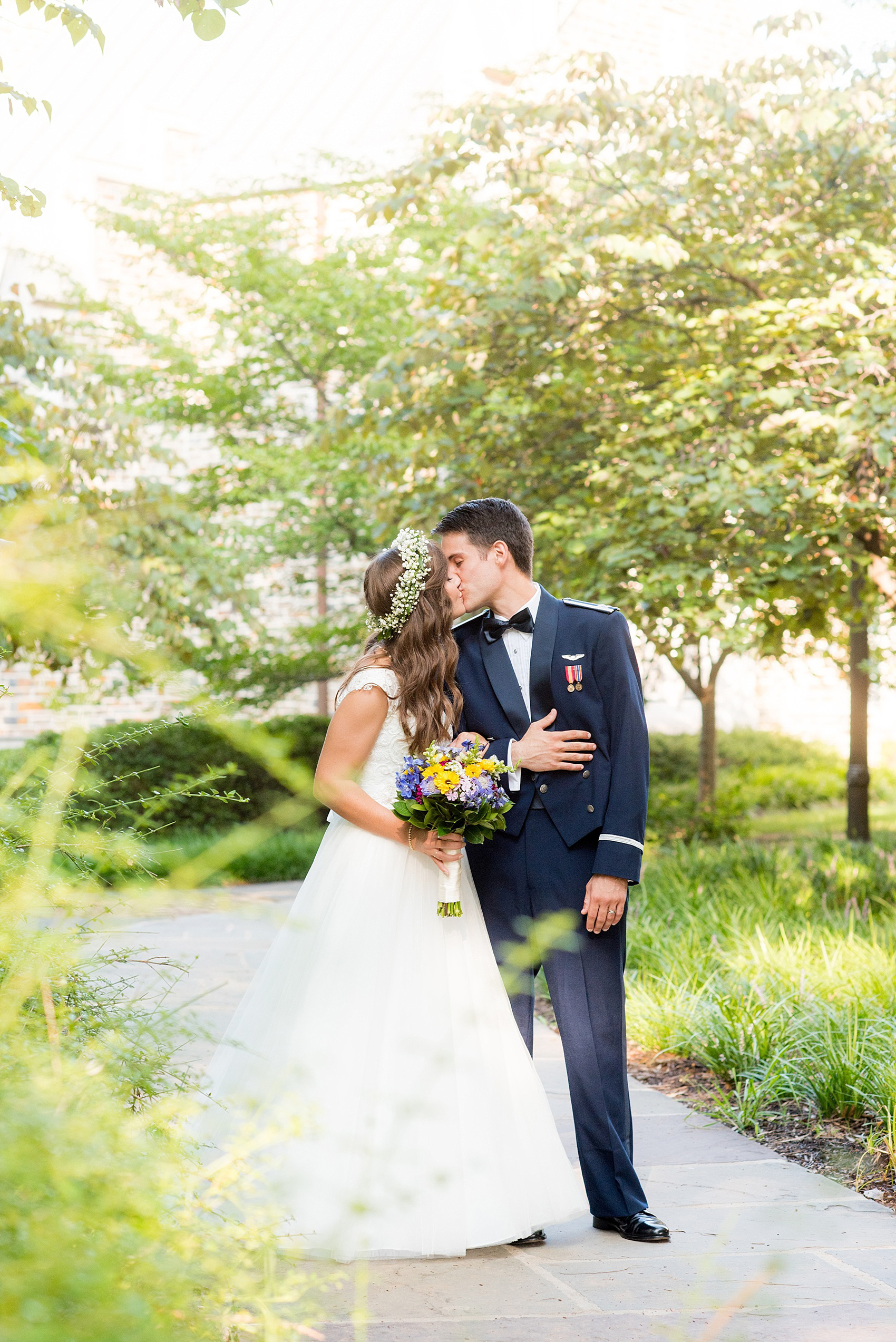 Mikkel Paige Photography photo of a Duke Chapel wedding in Durham, North Carolina. The bride and groom kiss in her lace cap gown and his navy blue Air Force uniform.