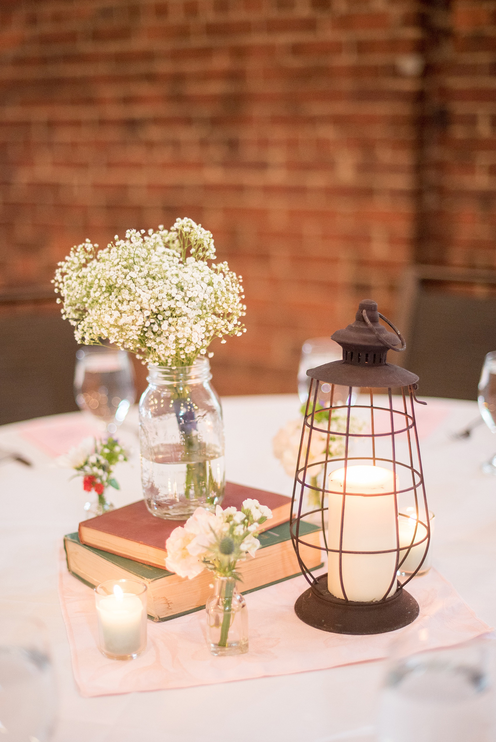Mikkel Paige Photography photo of a Top of the Hill reception in Chapel Hill, NC. A photo of the centerpieces including lanterns, candlelight, books and flowers.