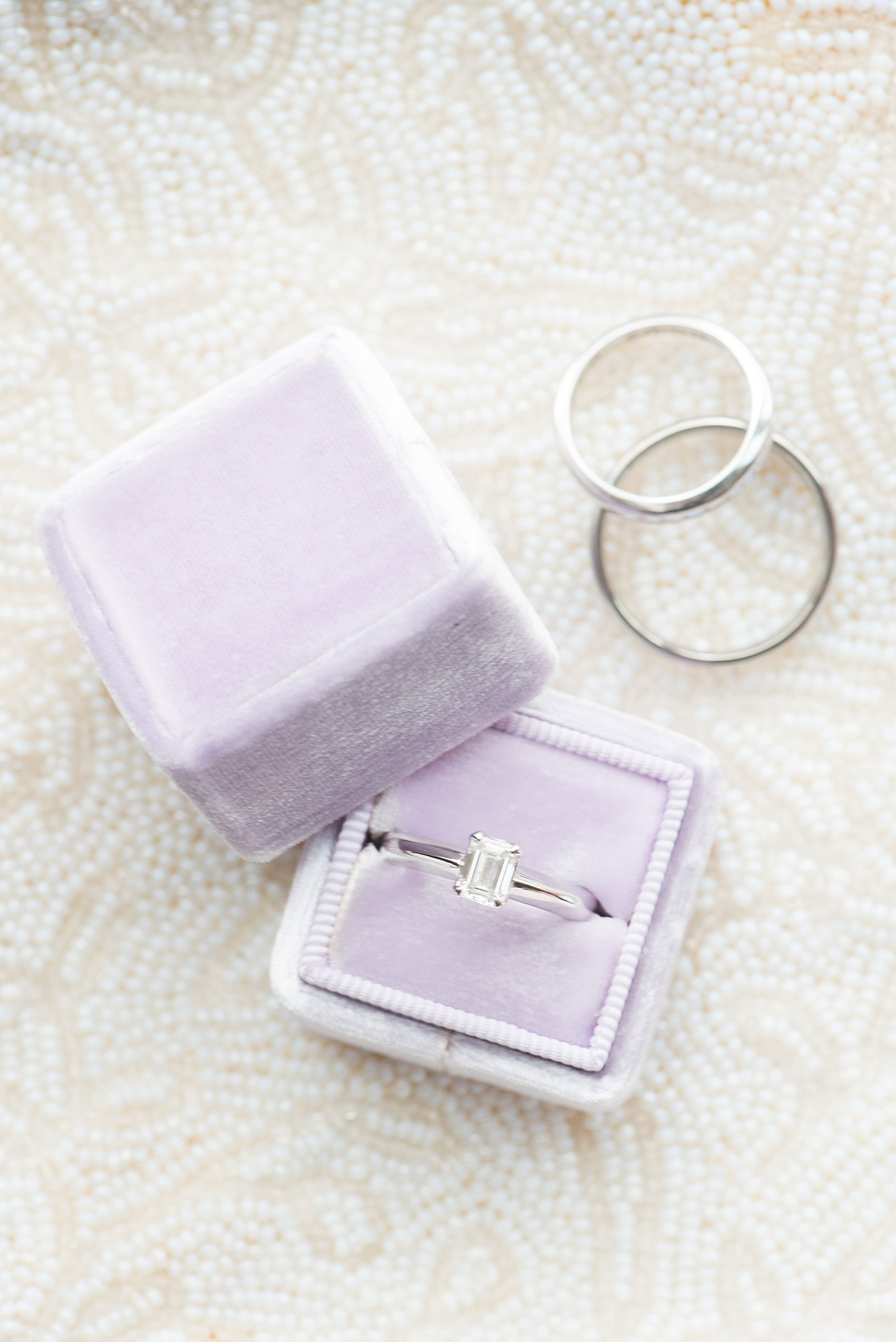 Mikkel Paige Photography photos of a NYC wedding at Tribeca Rooftop. A lavender purple Mrs. Box holds the bride's emerald cut diamond engagement ring.