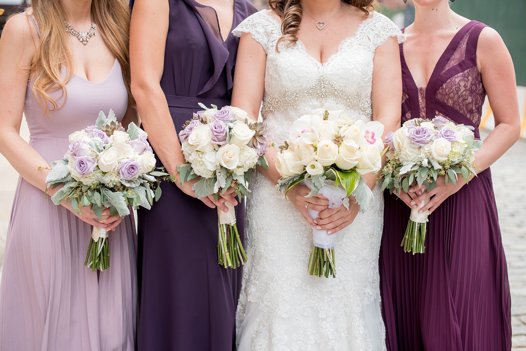 Mikkel Paige Photography photos of a NYC wedding at Tribeca Rooftop. An urban image of the wedding party in shades of mismatched purple dresses with rose and succulent bouquets.