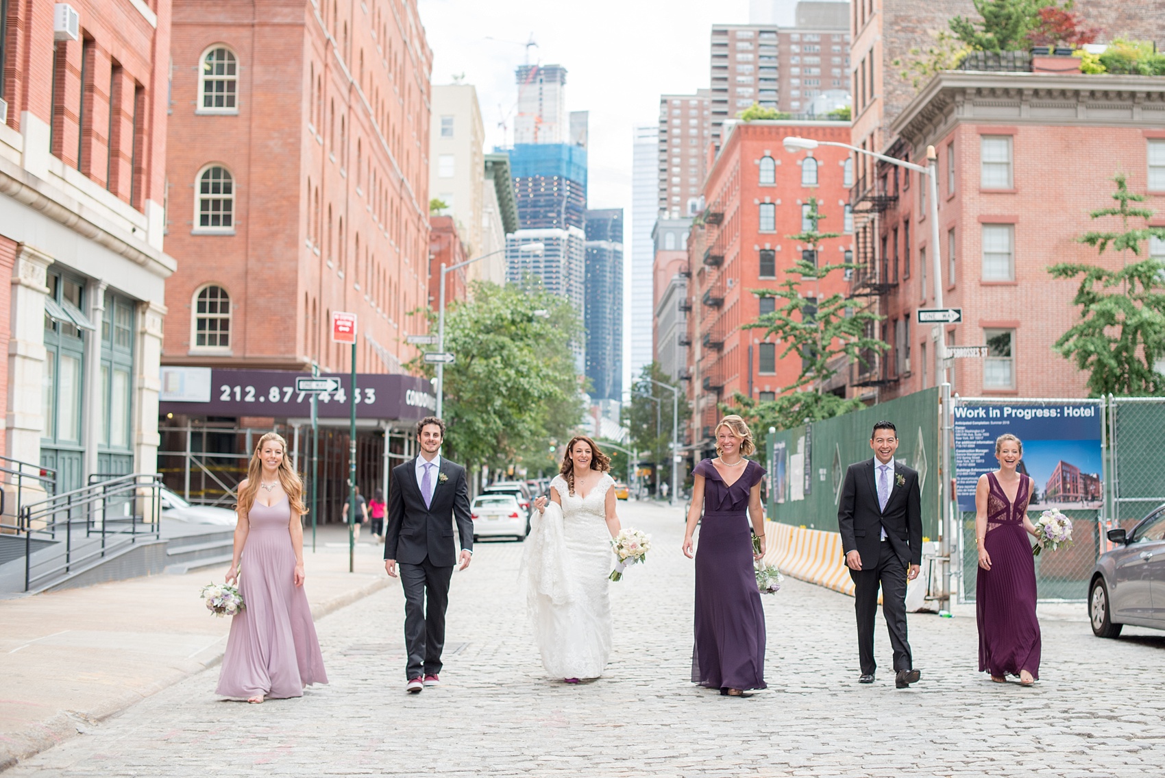 Mikkel Paige Photography photos of a NYC wedding at Tribeca Rooftop. An urban image of the wedding party in shades of mismatched purple dresses with rose and succulent bouquets.