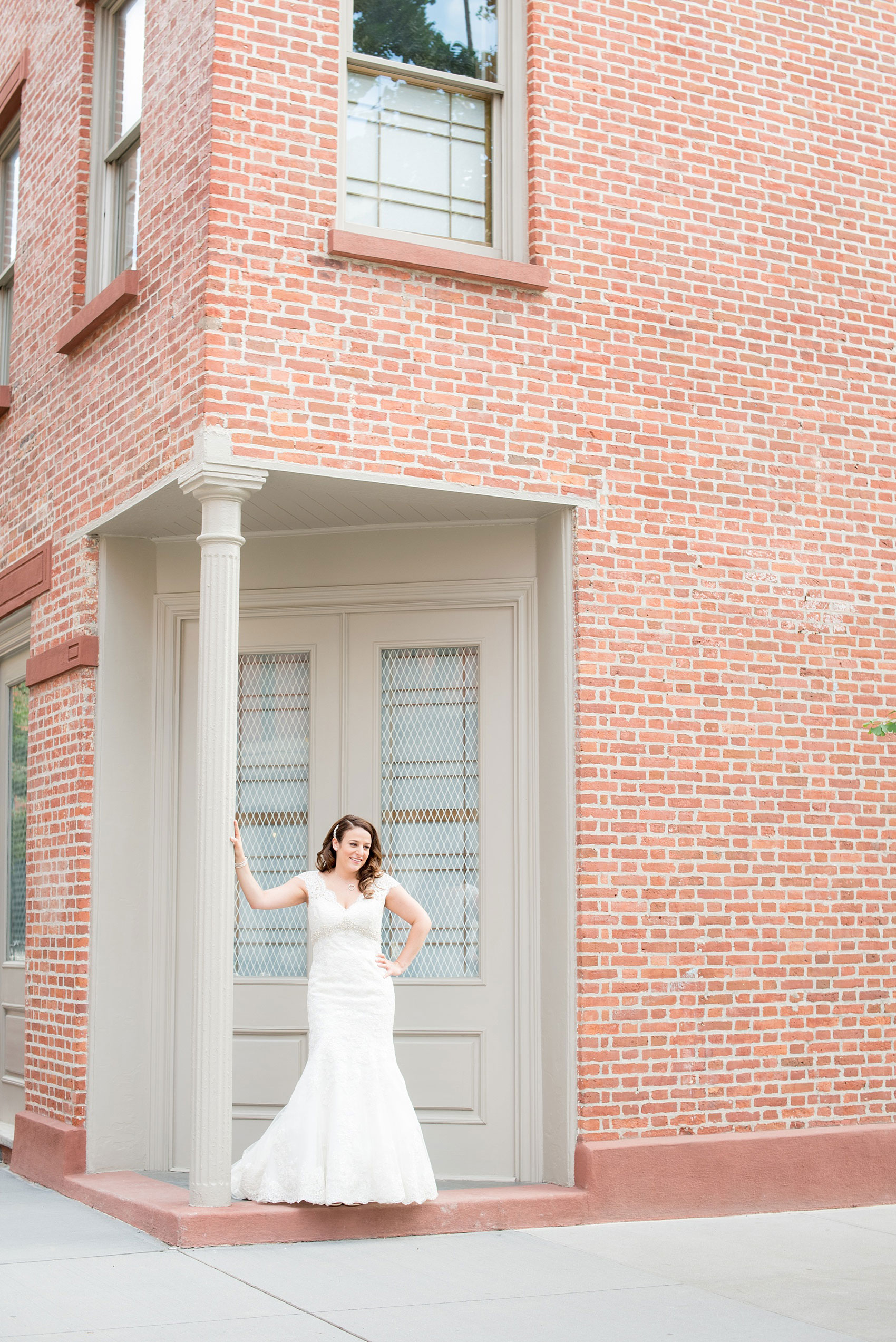 Mikkel Paige Photography photos of a NYC wedding at Tribeca Rooftop. An architectural brick wall image of the bride in her cap sleeve lace Anita Graham wedding gown.