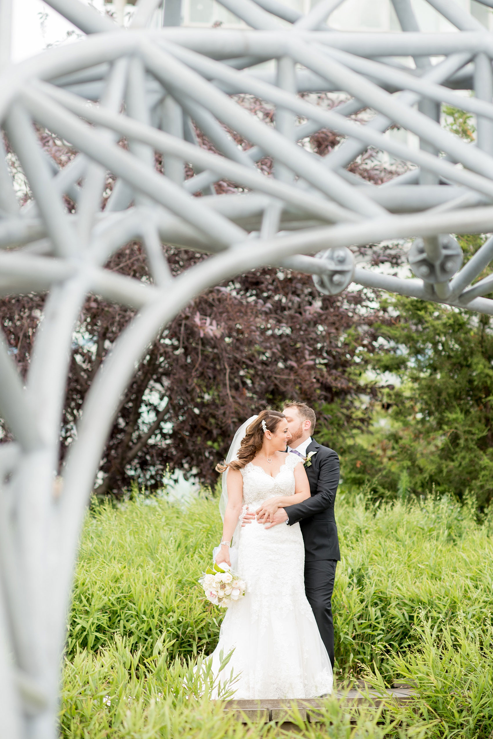 Mikkel Paige Photography photos of a NYC wedding at Tribeca Rooftop. An image of the bride and groom with a sculpture at Hudson River Park.