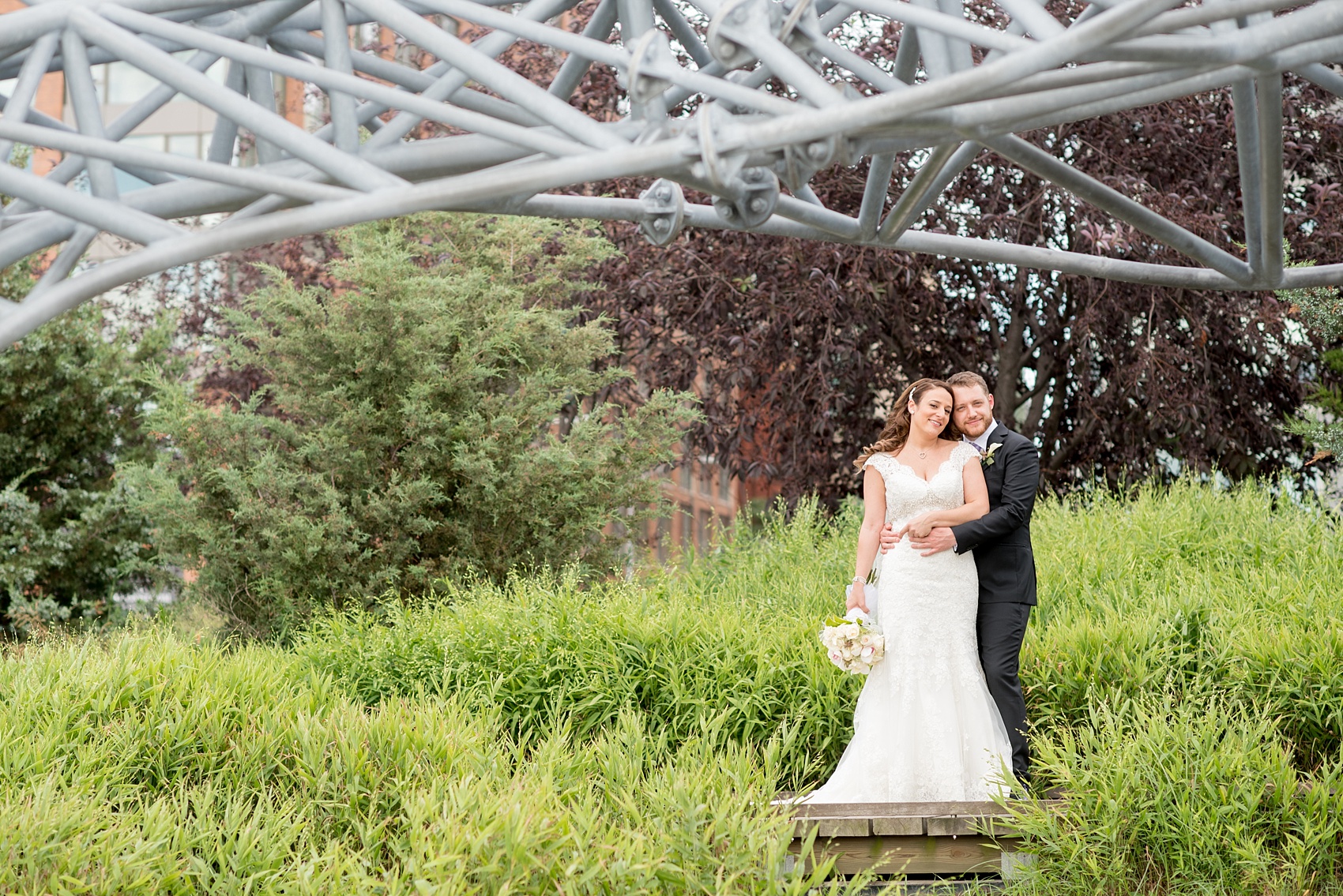 Mikkel Paige Photography photos of a NYC wedding at Tribeca Rooftop. An image of the bride and groom with a sculpture at Hudson River Park.