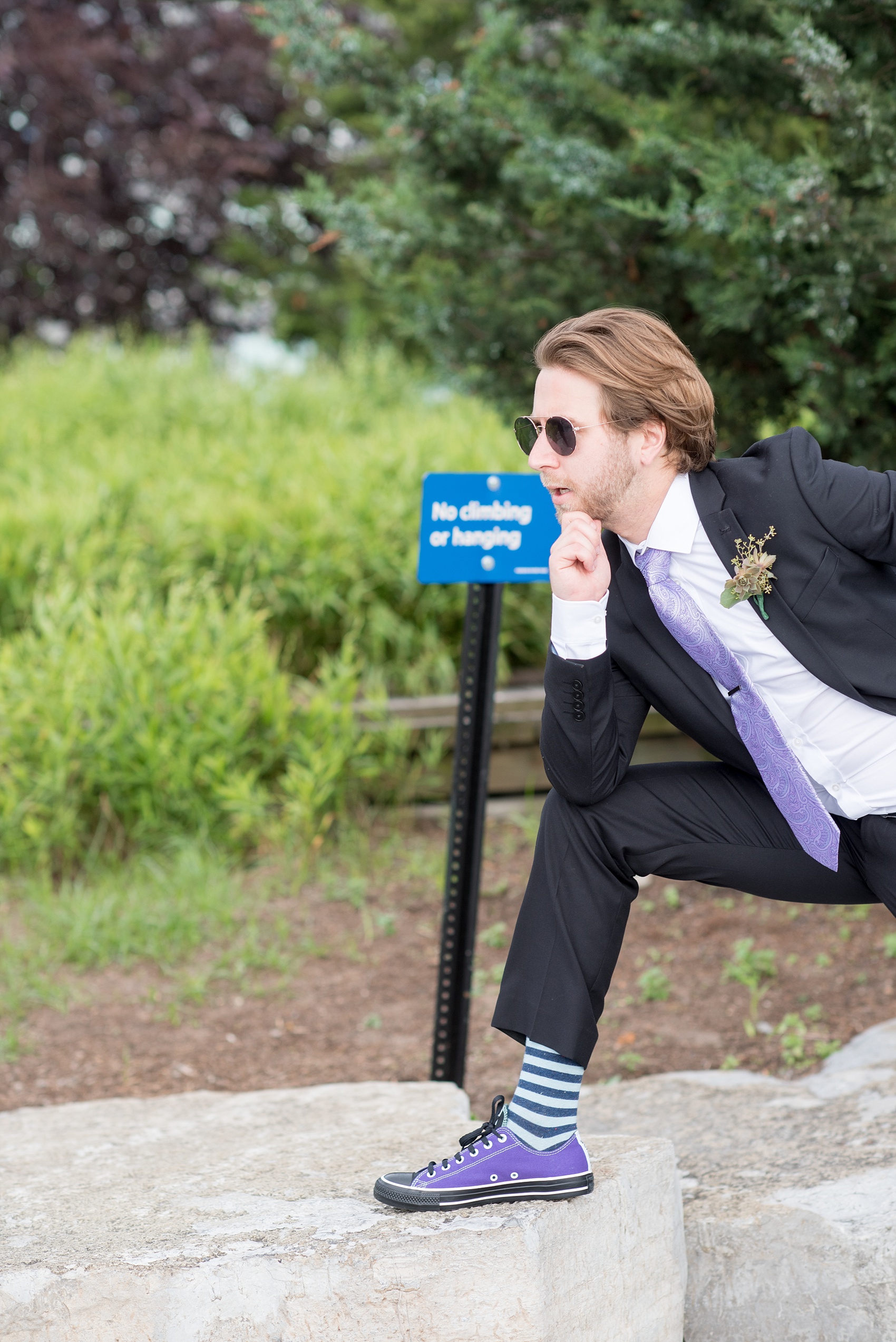 Mikkel Paige Photography photos of a NYC wedding at Tribeca Rooftop. An image of a groomsman in a purple tie and blue striped socks with custom Converse.