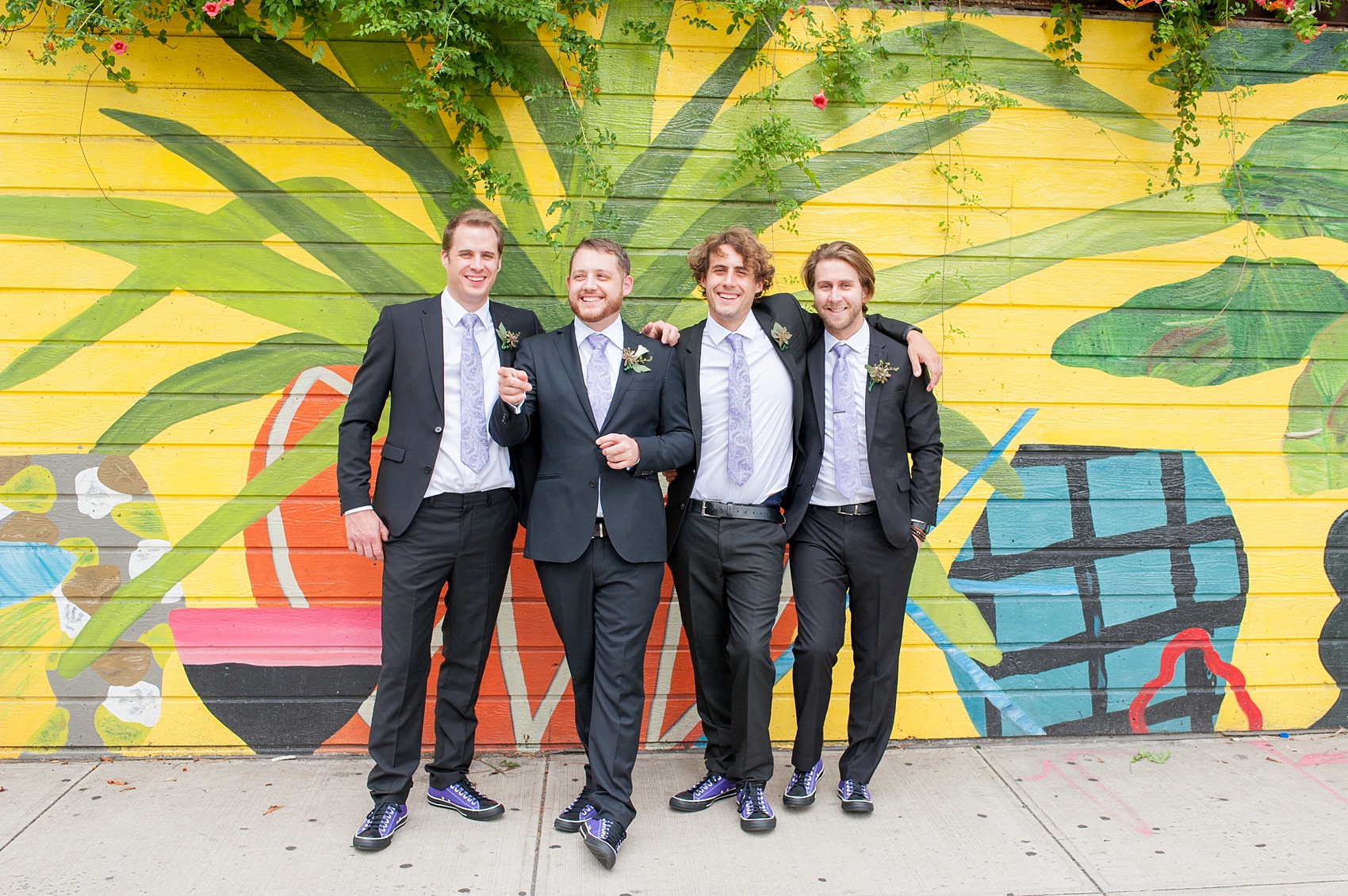 Mikkel Paige Photography photos of a NYC wedding at Tribeca Rooftop. An image of the groom and his groomsmen against a mural near The James Hotel.