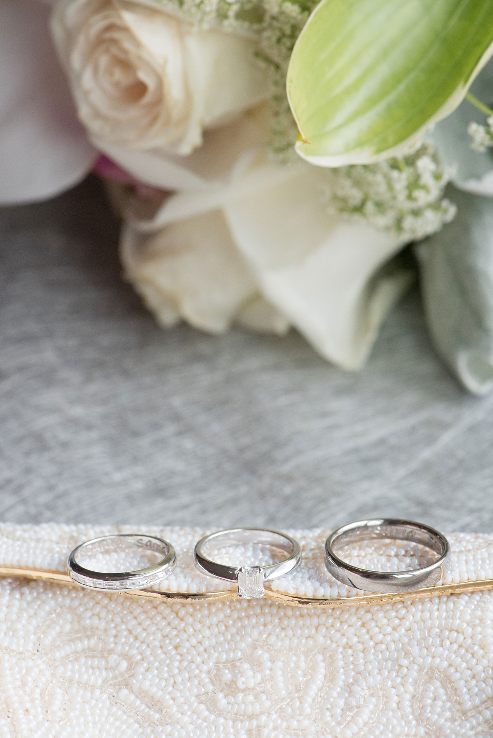 Mikkel Paige Photography photos of a NYC wedding at Tribeca Rooftop. An image of white gold wedding bands with emerald cut diamonds.