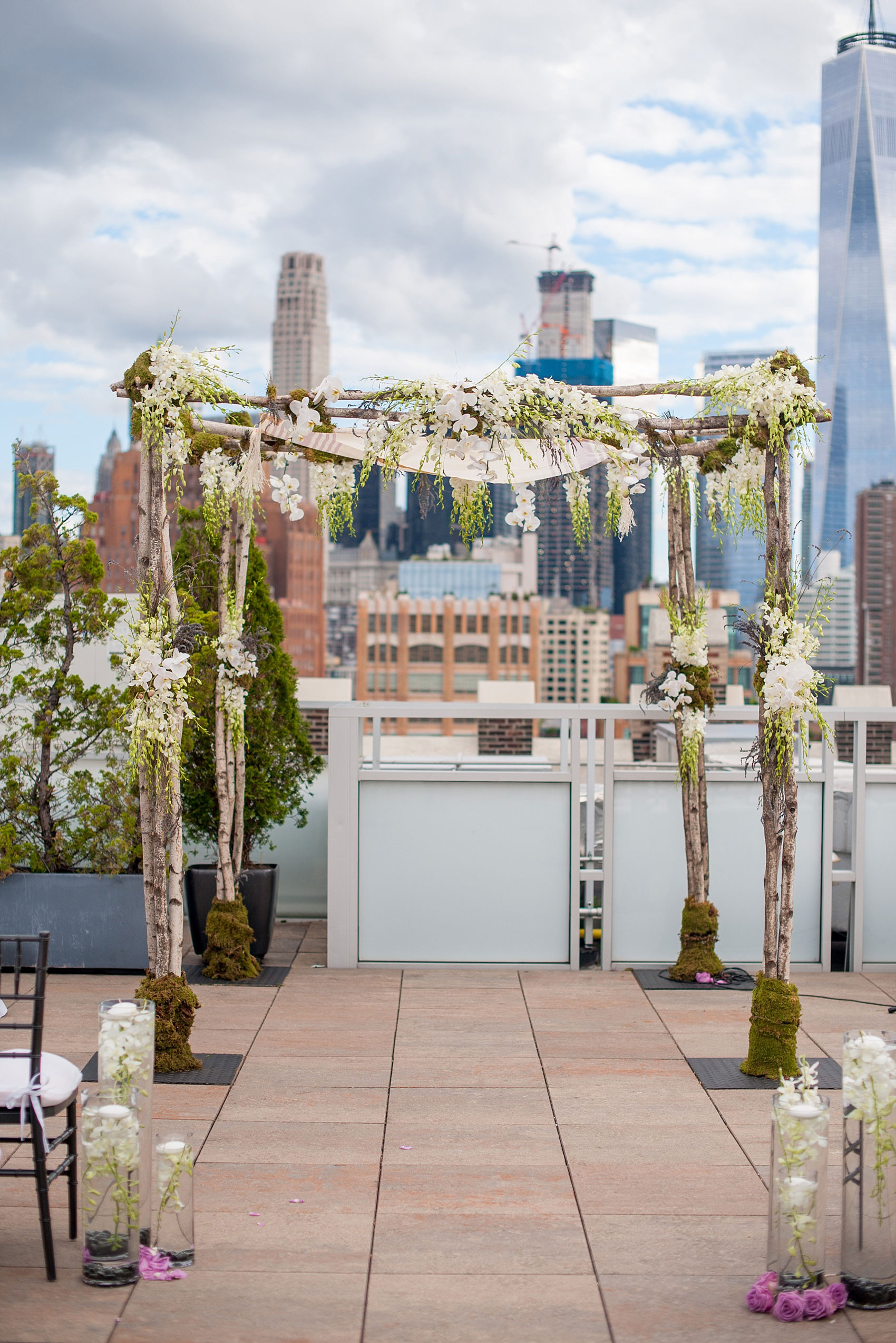 Mikkel Paige Photography photos of a NYC wedding at Tribeca Rooftop. An image of the chuppah with birch branches, moss and hanging orchids.