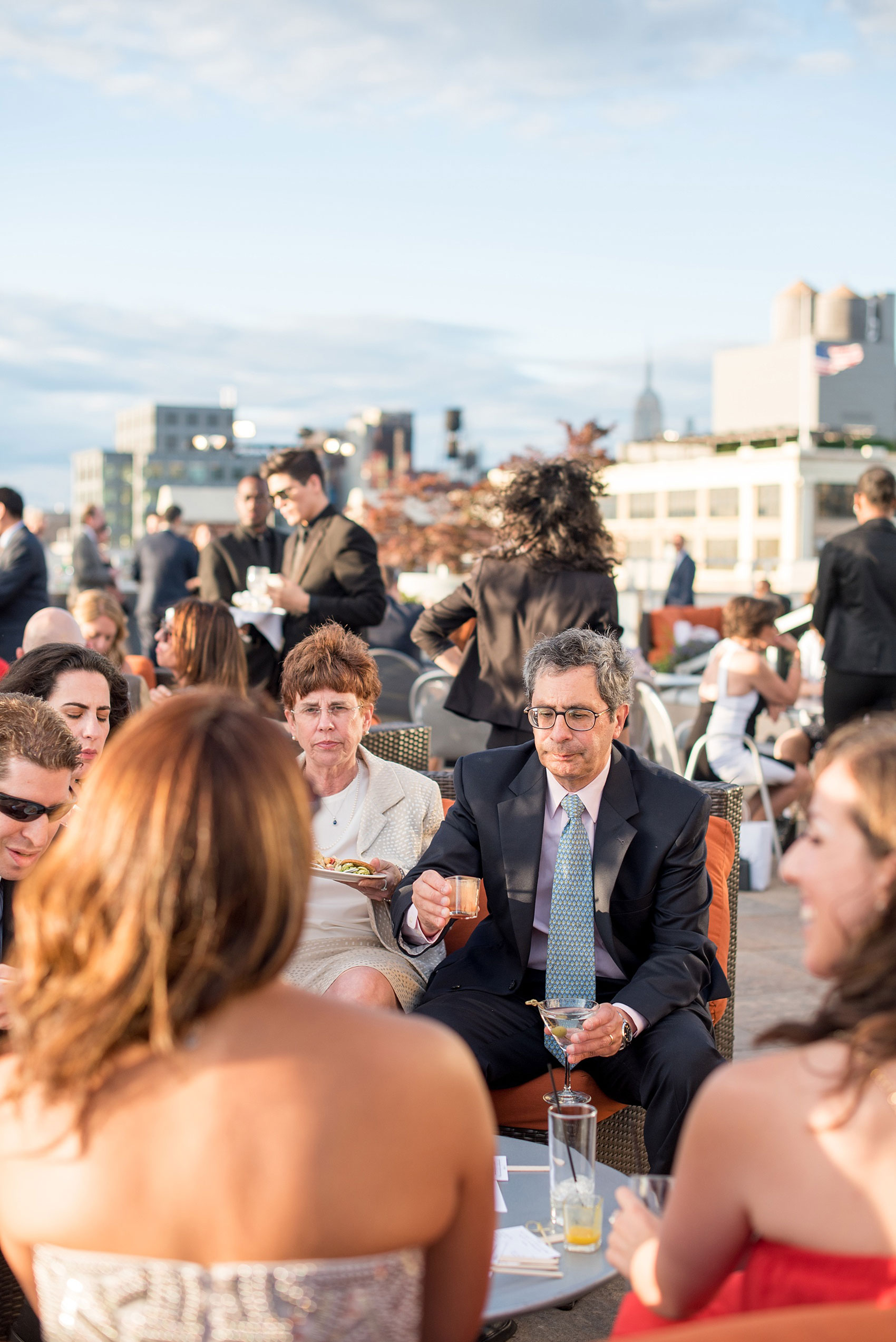 Mikkel Paige Photography photos of a NYC wedding at Tribeca Rooftop. An image of the outdoor cocktail hour with the Empire State Building in the distance.