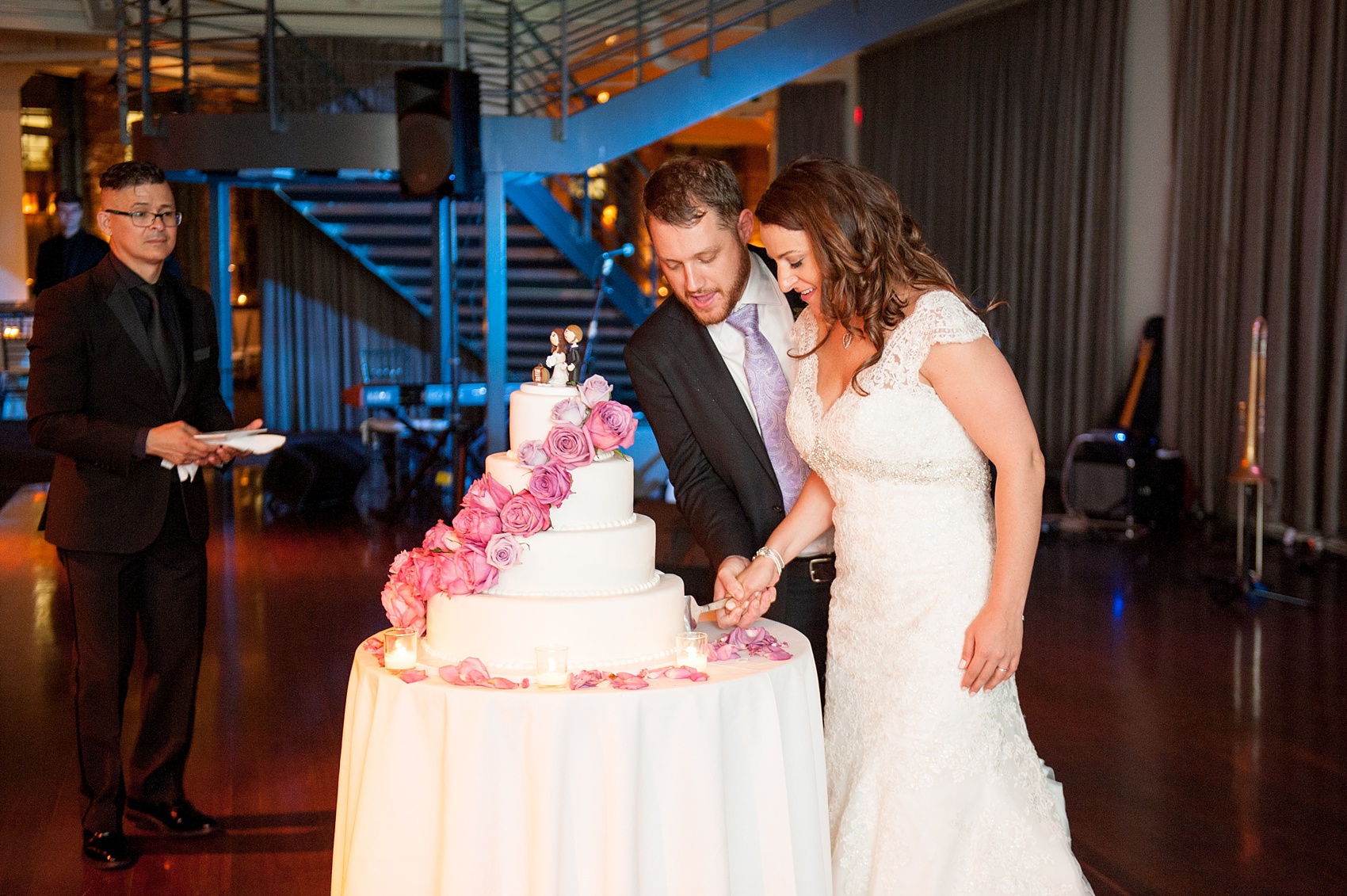 Mikkel Paige Photography photos of a NYC wedding at Tribeca Rooftop. Image of the bride and groom cutting their white fondant, purple rose cake.