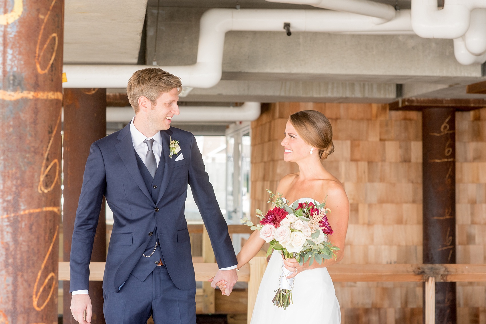 Mikkel Paige Photography photos of a Bay Head Yacht Club nautical wedding. The bride wore a tulle overlay for a second look with her white sweetheart neckline gown and the groom wore a navy blue three-piece suit.