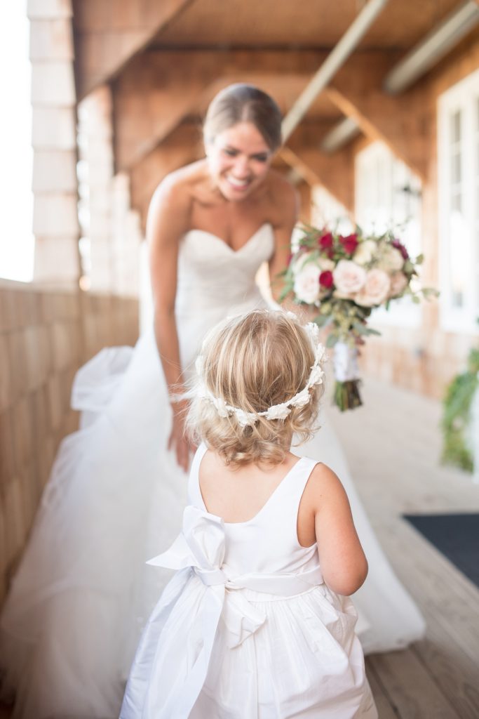 Mikkel Paige Photography photos of a Bay Head Yacht Club nautical wedding. The bride greets the flower girl in her white floral crown.