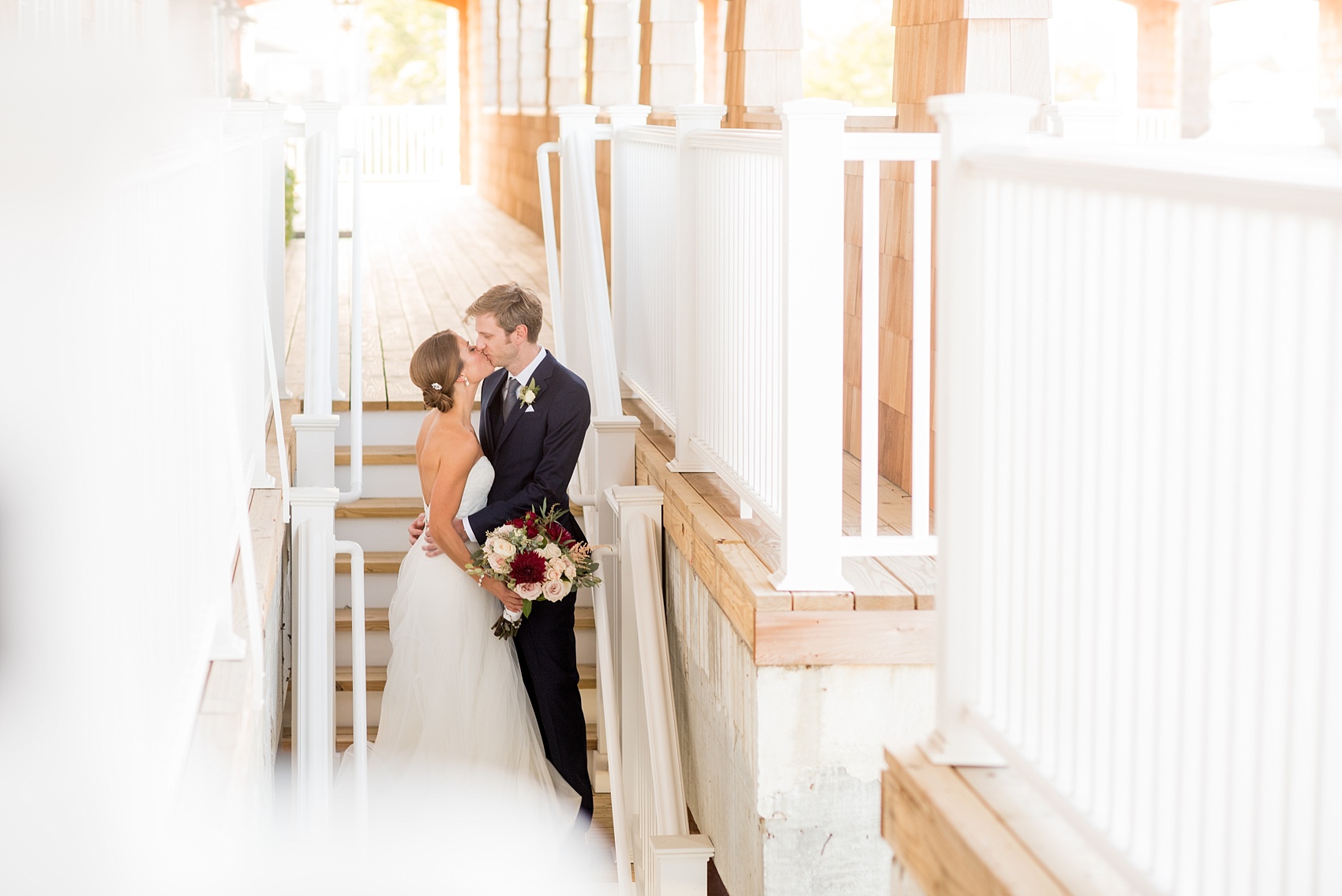 Mikkel Paige Photography photos of a Bay Head Yacht Club nautical wedding. The bride and groom kiss in a staircase image.