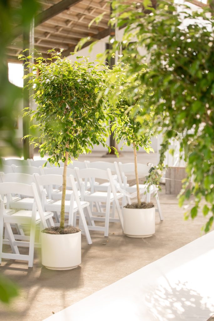 Mikkel Paige Photography picture of a Bay Head Yacht Club nautical wedding. A boathouse ceremony with ficus trees lining the aisle and vintage boat exit.