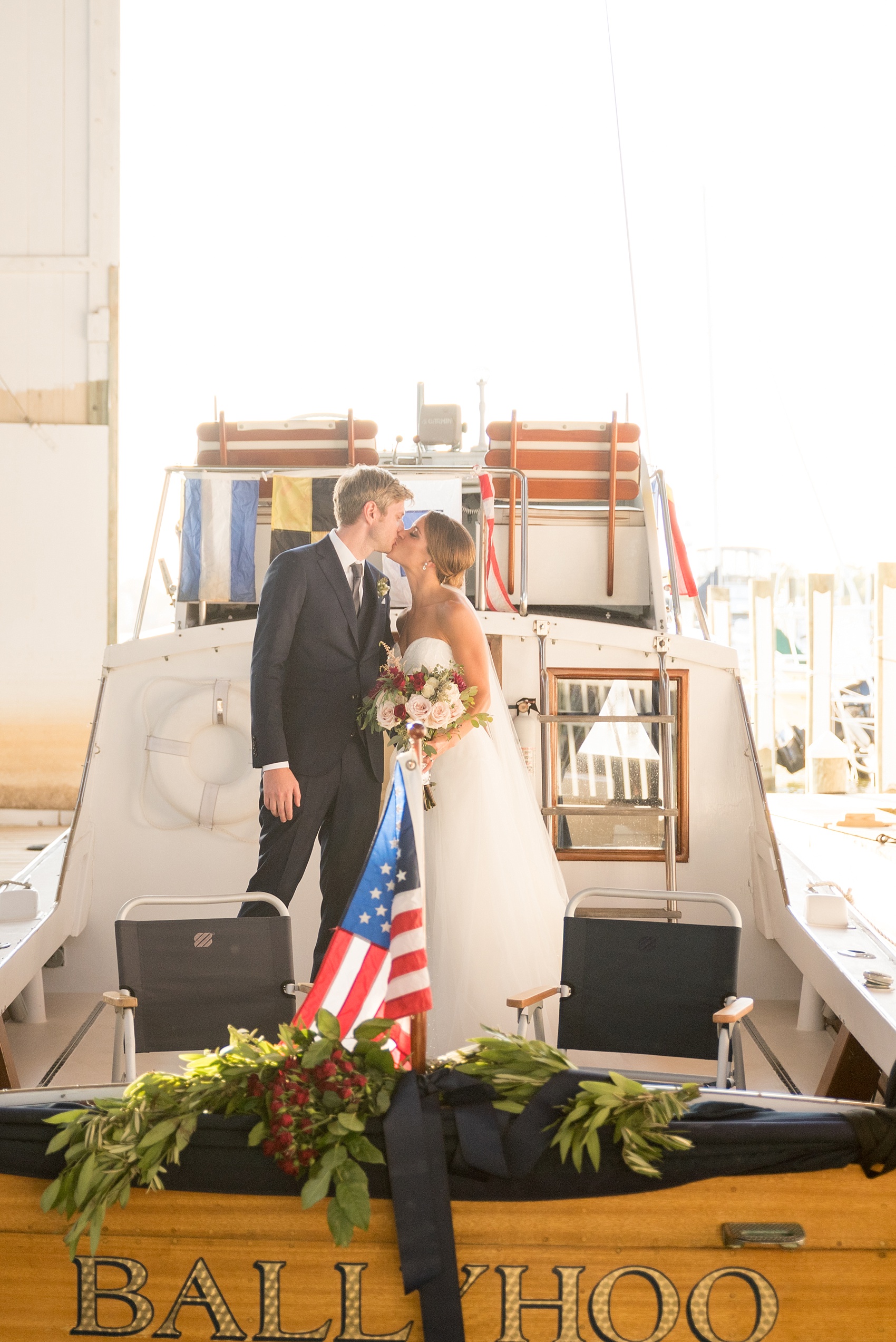 Mikkel Paige Photography picture of a Bay Head Yacht Club nautical wedding. A boathouse ceremony with the bride and groom exiting on a vintage boat.