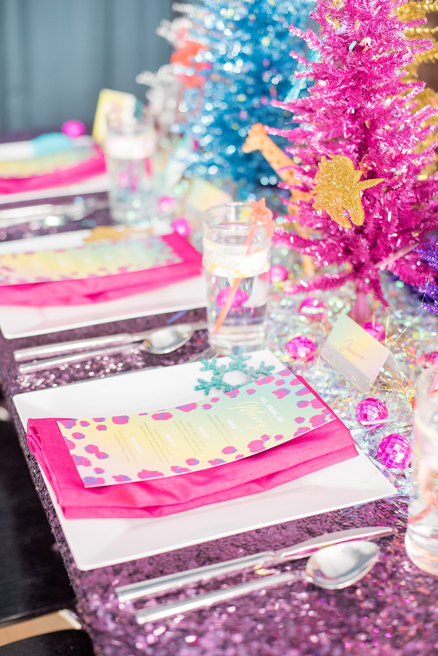 Mikkel Paige Photography photo of a holiday party with a Lisa Frank theme, with a purple sequin tablecloth, colorful Christmas trees, and confetti accents