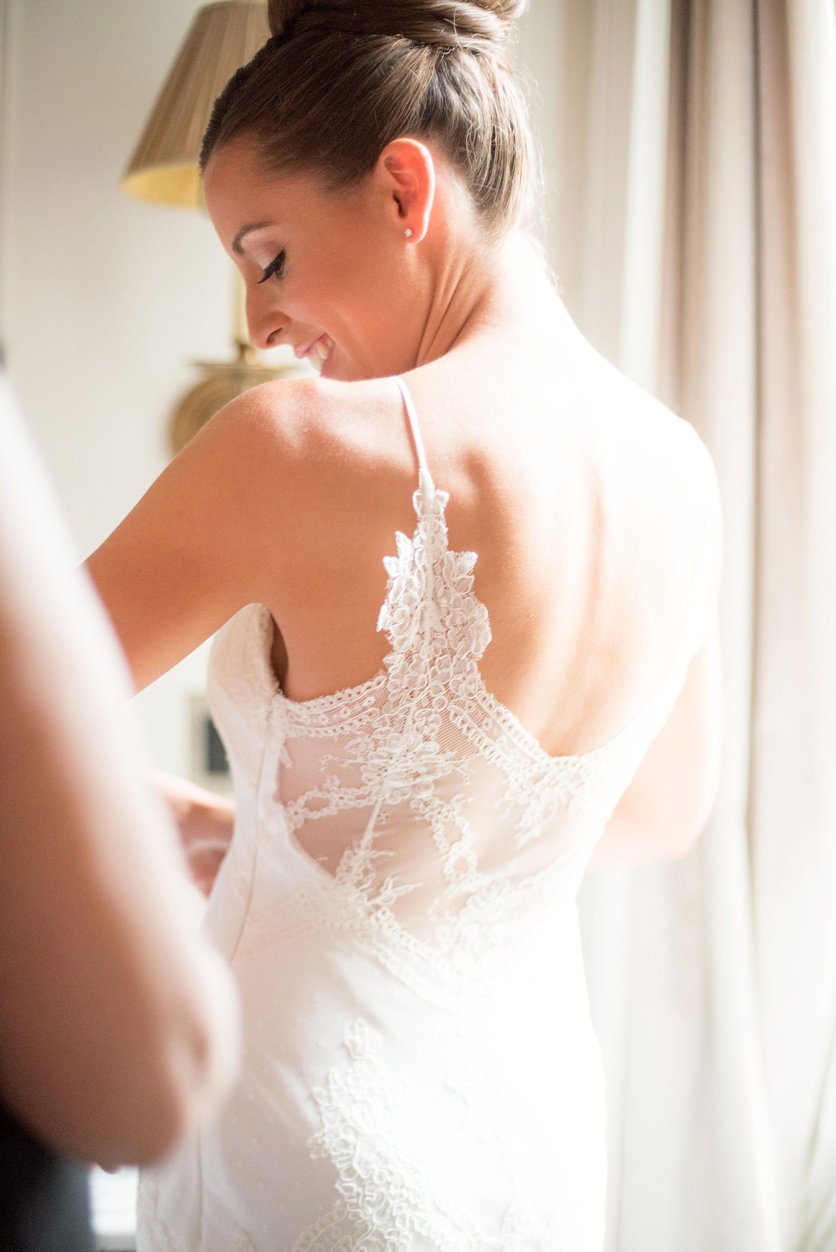 Mikkel Paige Photography captures a luxury wedding in NYC. The bride's mom helps her get dressed in her David Fielden wedding from Kleinfeld's at The Marlton Hotel.