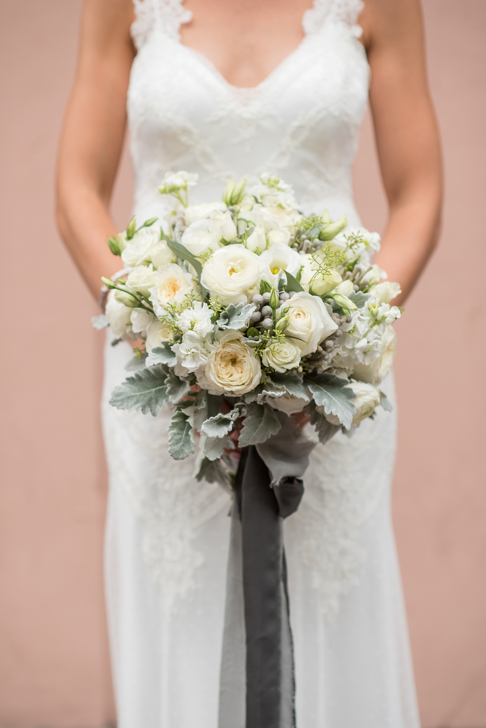 Mikkel Paige Photography photos of a luxury wedding in NYC. Portrait picture of the bride in her form fitting David Fielden wedding gown from Kleinfeld's, holding her white bouquet with ranunculus and brunia.