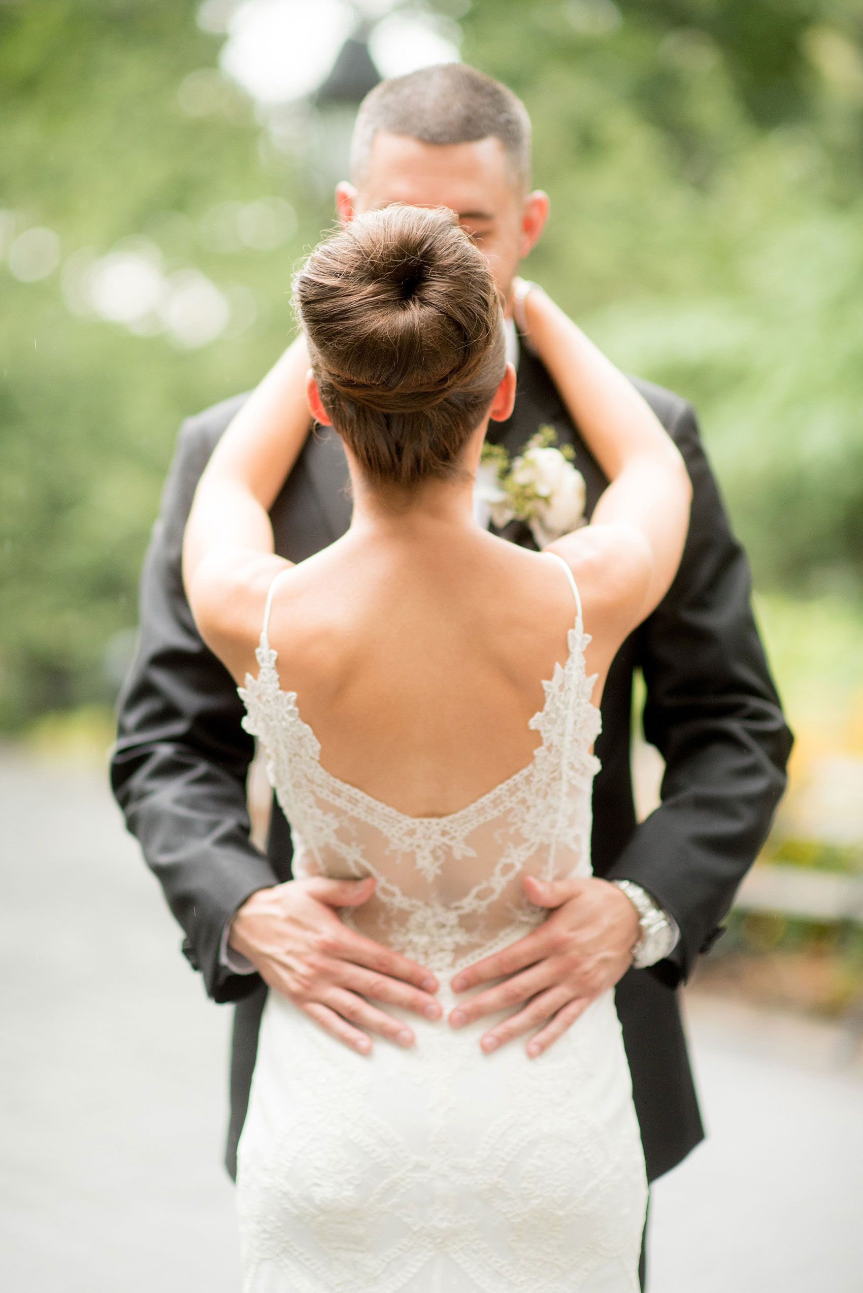 Mikkel Paige Photography photos of a luxury wedding in NYC. Image of the bride and groom in Washington Square Park. The bride had a lace back on her gown and high bun up do.