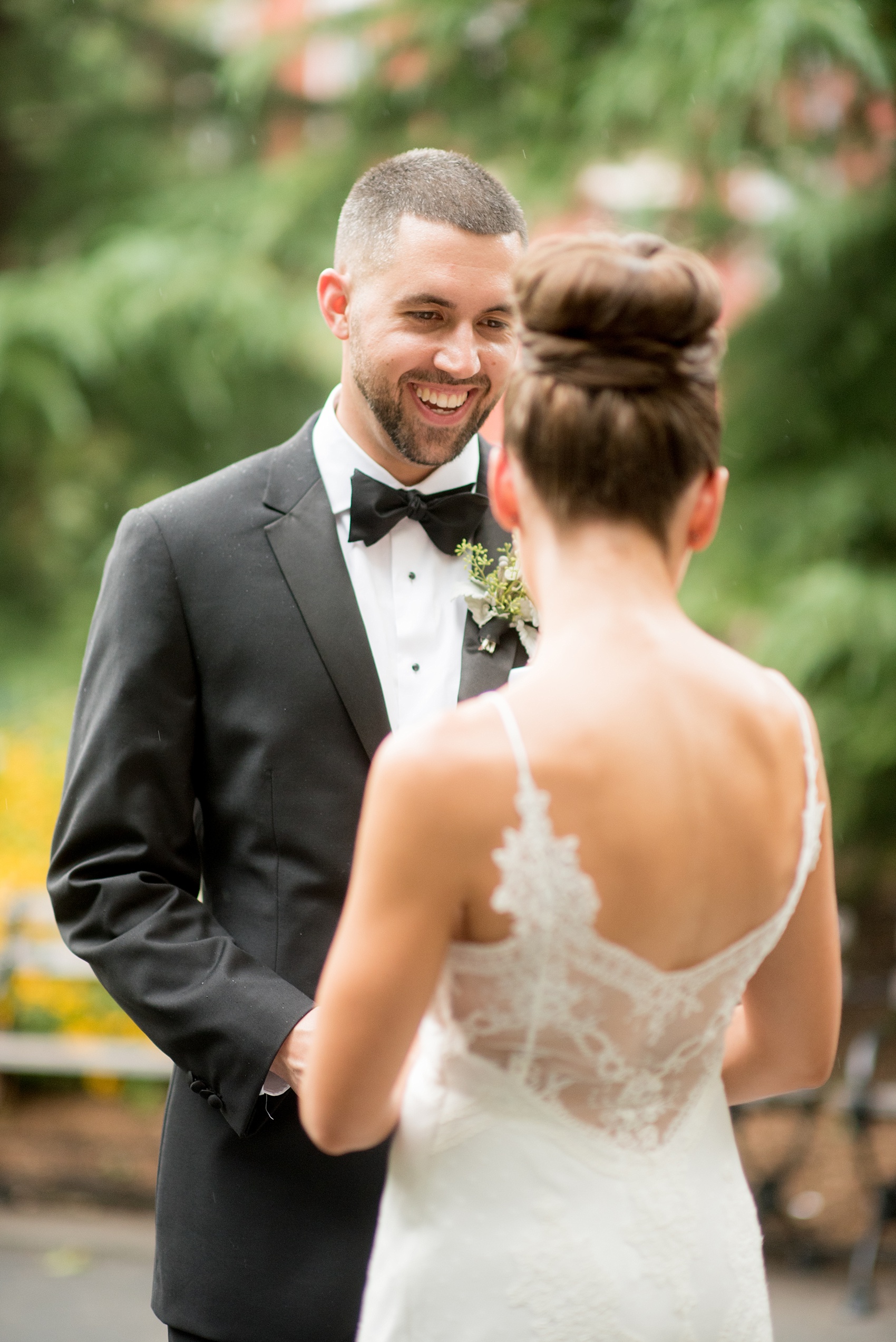 Mikkel Paige Photography photos of a luxury wedding in NYC. Image of the bride and groom in Washington Square Park. The bride had a lace back on her gown and high bun up do.