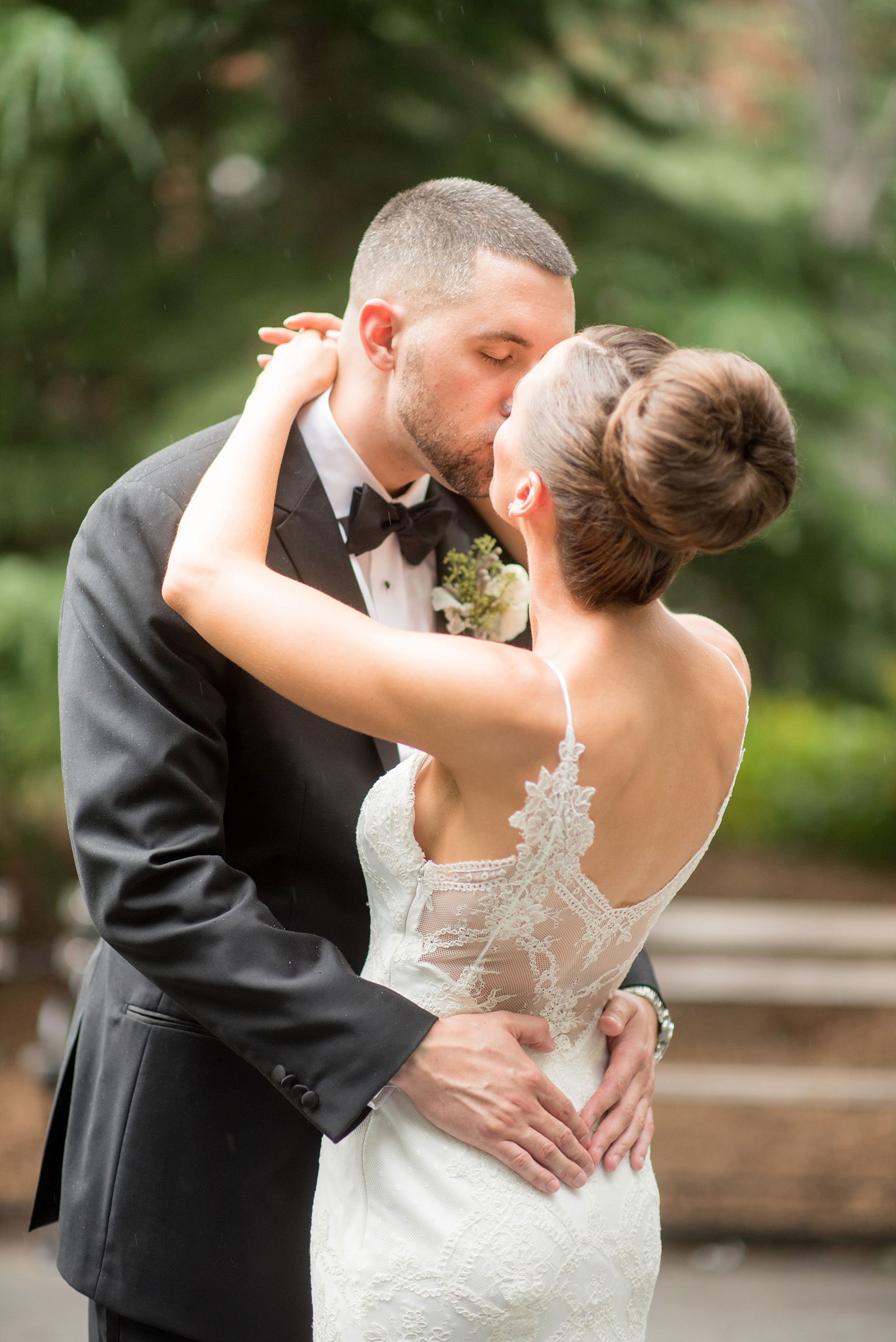 Mikkel Paige Photography photos of a luxury wedding in NYC. Image of the bride and groom in Washington Square Park. The bride had a lace back on her gown and high bun up do.