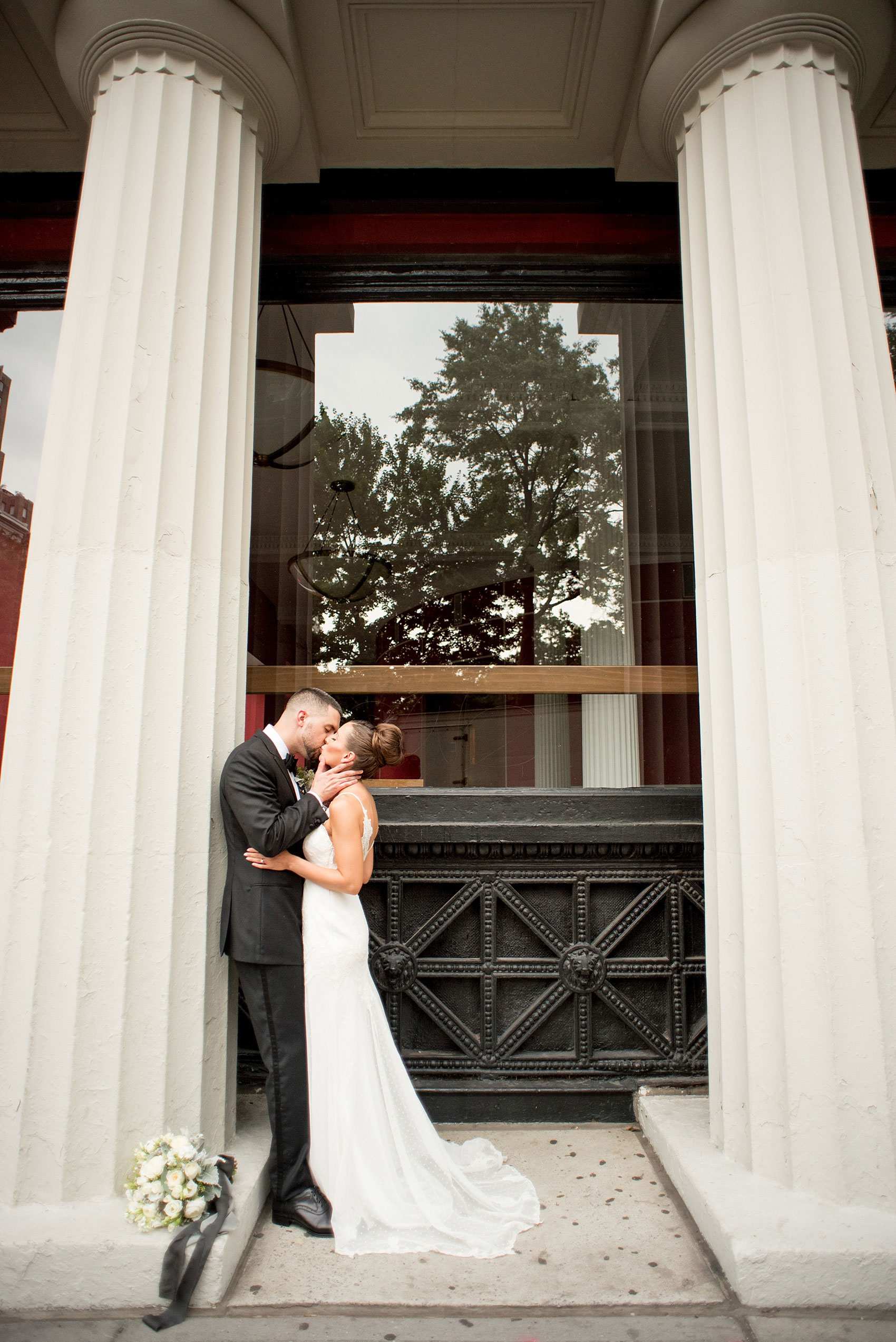 Mikkel Paige Photography photos of a luxury wedding in NYC. Image of the bride and groom near Washington Square Park kissing between white columns.