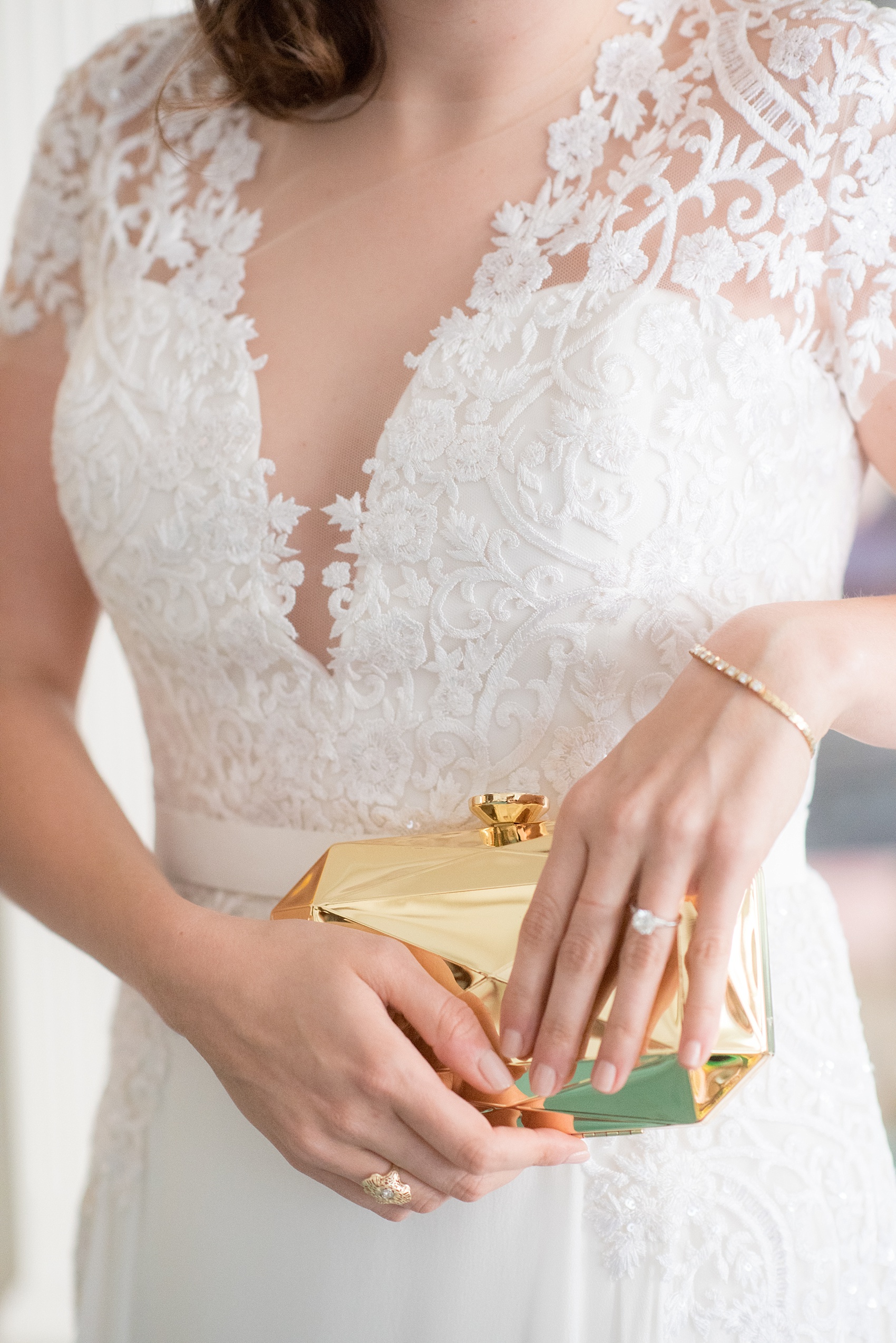 Mikkel Paige Photography photos of a wedding at Prospect Park Boathouse in Brooklyn, NY. A candid picture of the bride's gold metal clutch and Reem Acra lace gown.
