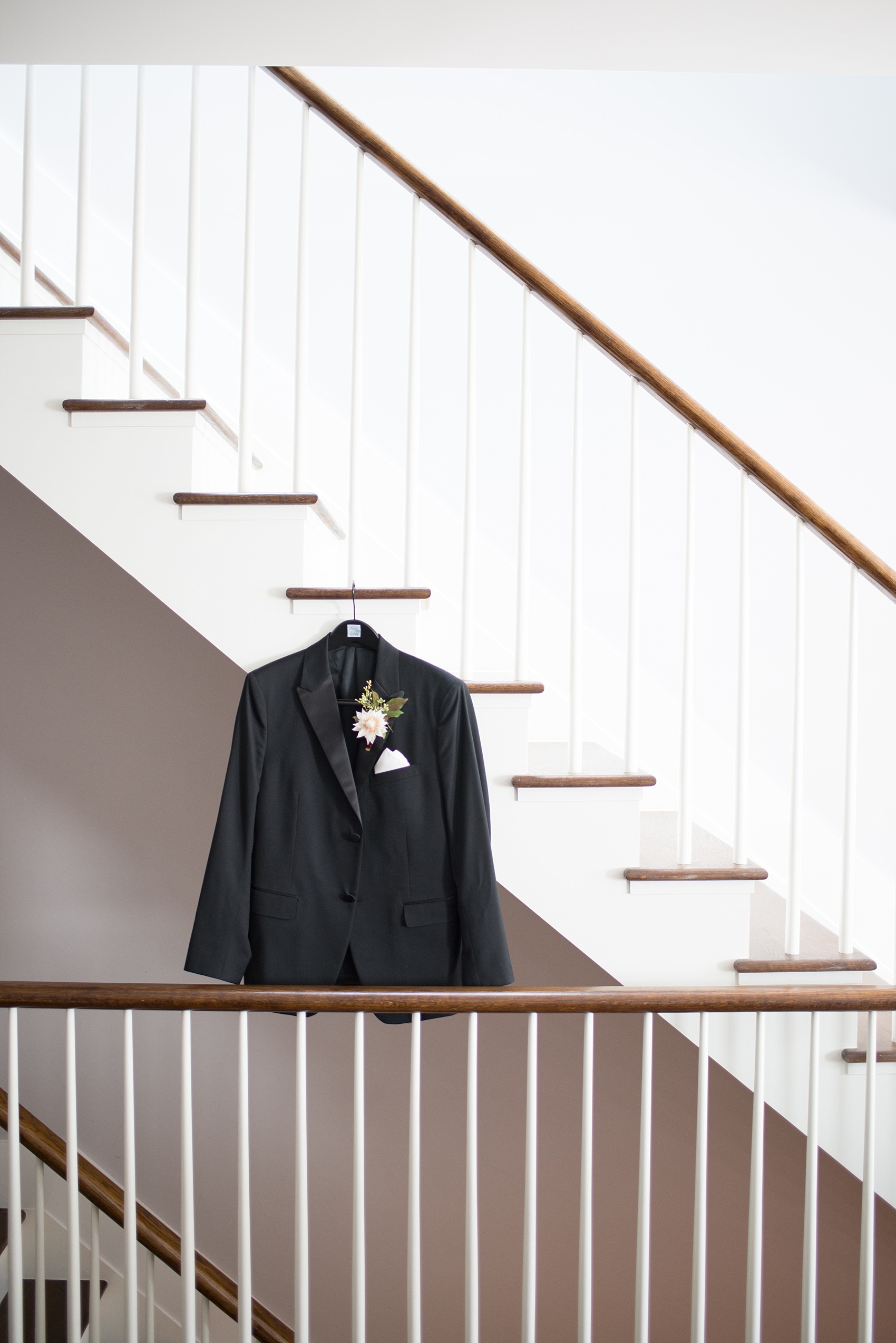 Mikkel Paige Photography photos of a wedding at Prospect Park Boathouse in Brooklyn, NY. A photo of the groom's black jacket on the staircase of a mod Air BnB in NYC.