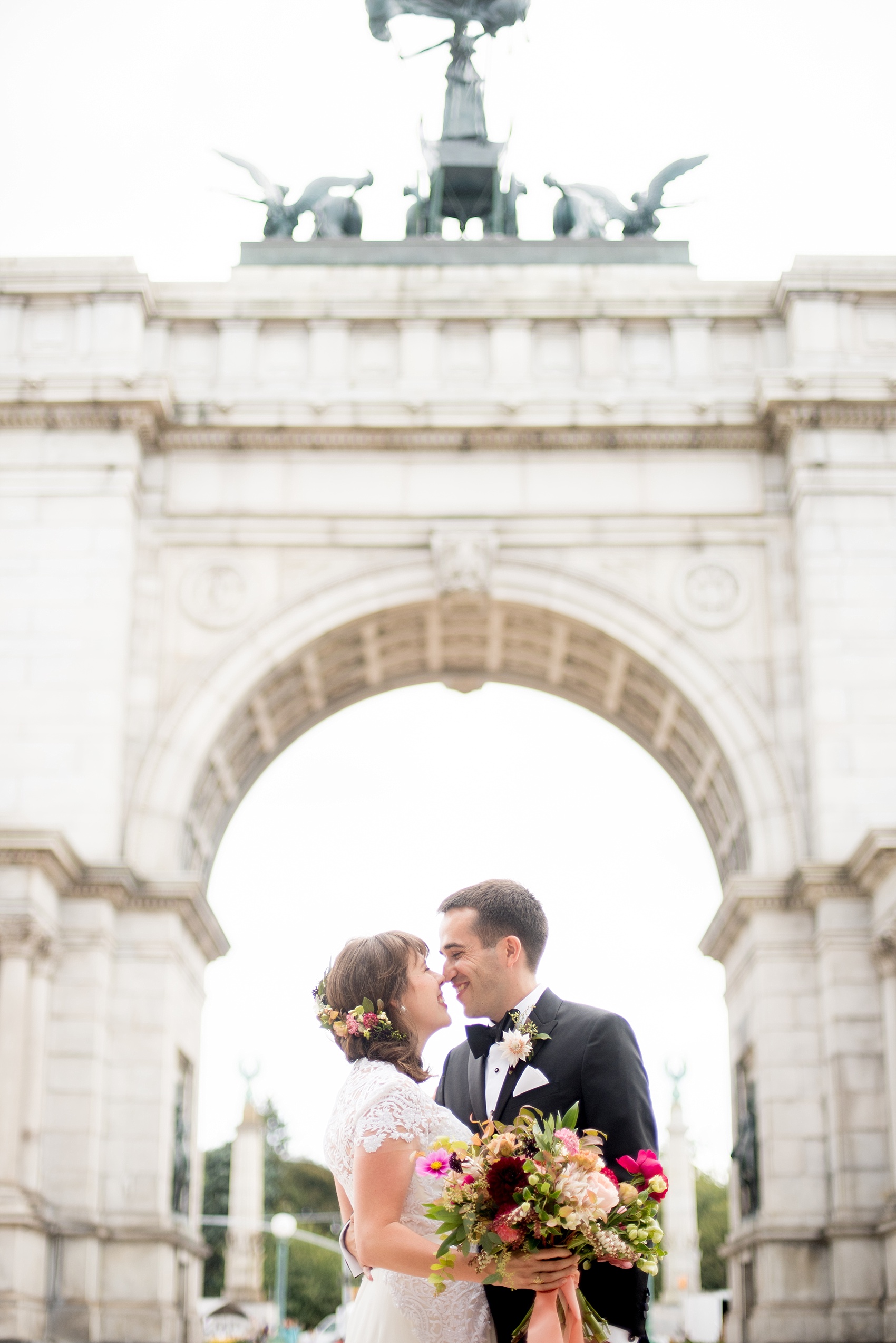 Mikkel Paige Photography photos of a wedding first look at Grand Army Plaza for a Prospect Park Boathouse ceremony in Brooklyn, NY. The bride and groom have a candid moment under the arch.