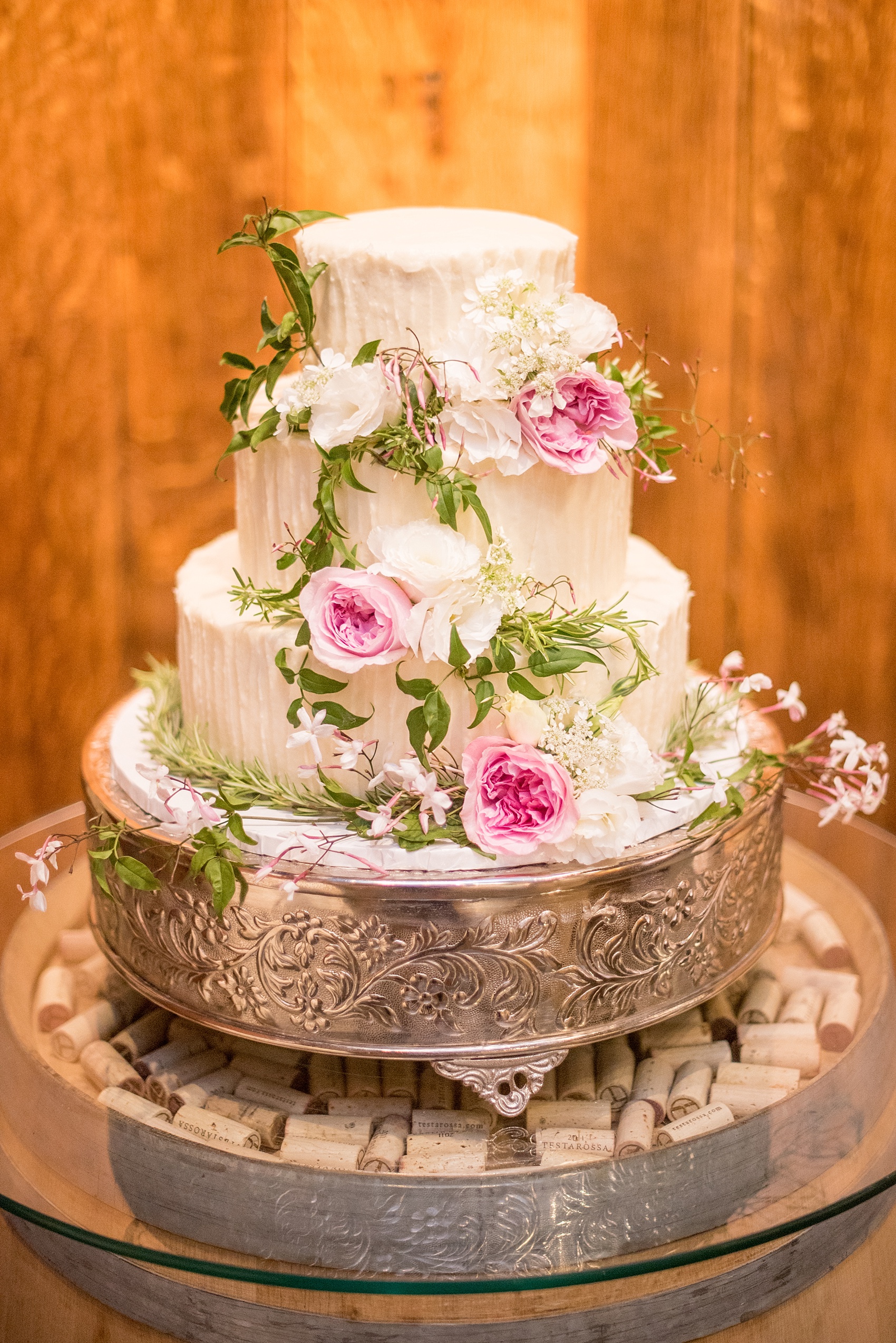 Mikkel Paige Photography cake photo at a Testarossa Winery wedding in Los Gatos, California. White buttercream stacked rounds with fresh pink and green garden rose flowers.