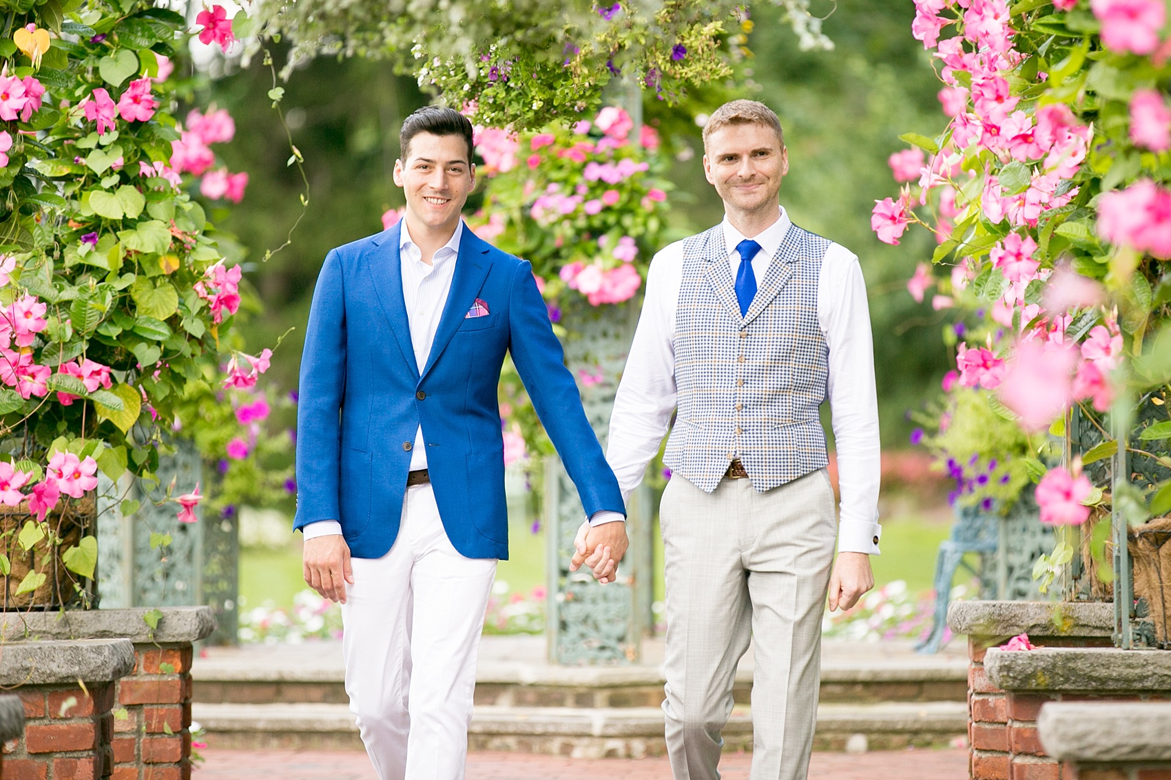 Mikkel Paige Photography photos of a gay wedding at The Manor in West Orange, NJ. The grooms walk to their outdoor summer ceremony on a rose petal carpet under live arches and greenery.