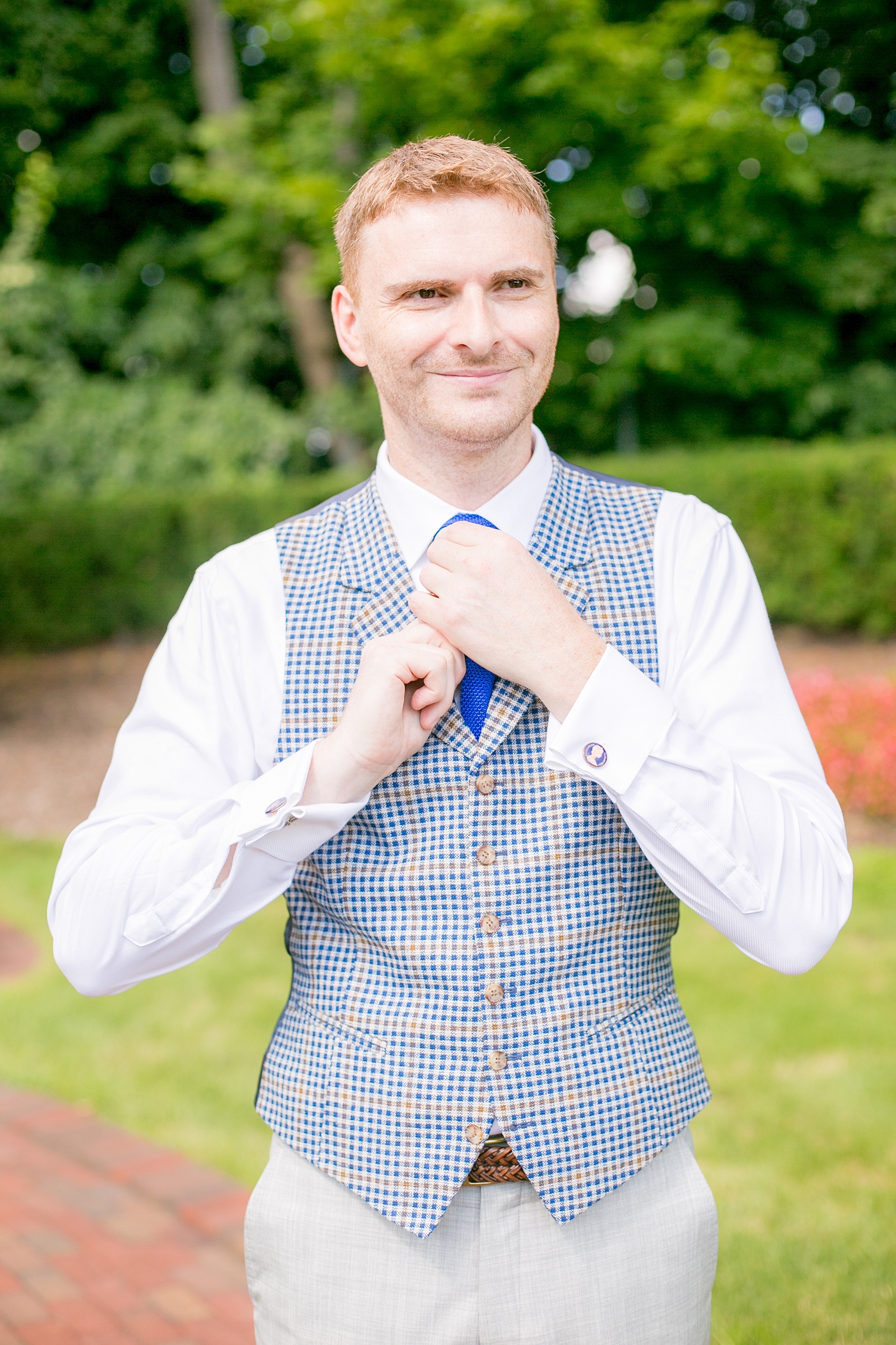 Mikkel Paige Photography photos of a summer, daytime gay wedding. An image of the groom in a blue and white plaid vest at The Manor, in West Orange New Jersey.