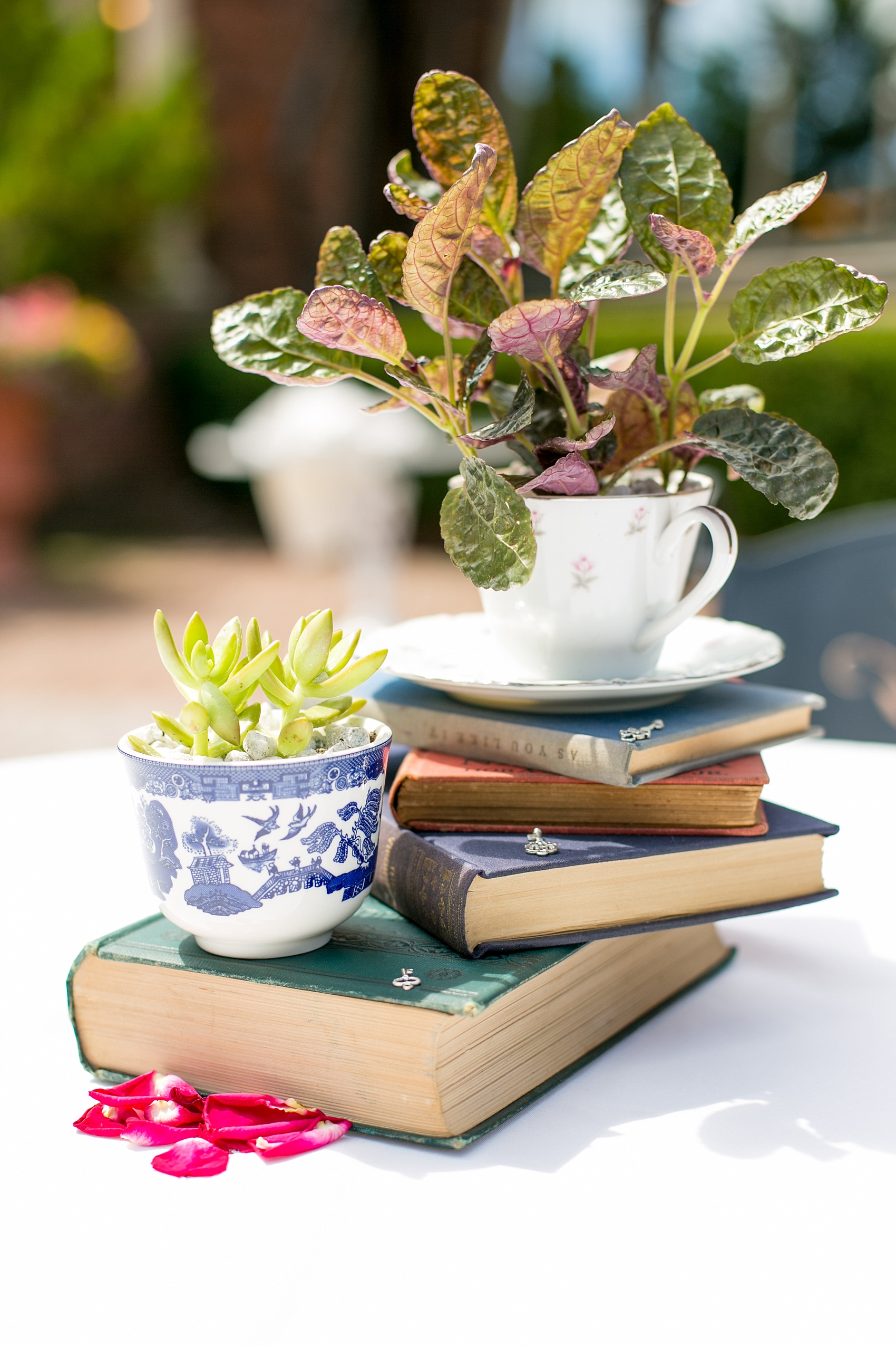 Mikkel Paige Photography photos of a gay wedding, at The Manor in West Orange, NJ. Image of their reception centerpieces including vintage books, teacups and succulent plants.