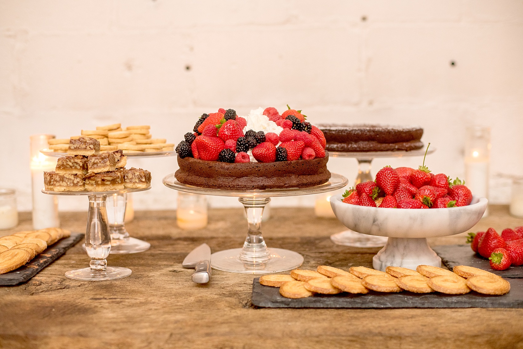 Mikkel Paige Photography photos of a wedding rehearsal dinner at Aterlier Roquette, Brooklyn. A romantic intimate setting for a small gathering in a warehouse district. Dessert was presented on a farm table, with fresh strawberries and flourless chocolate cake.