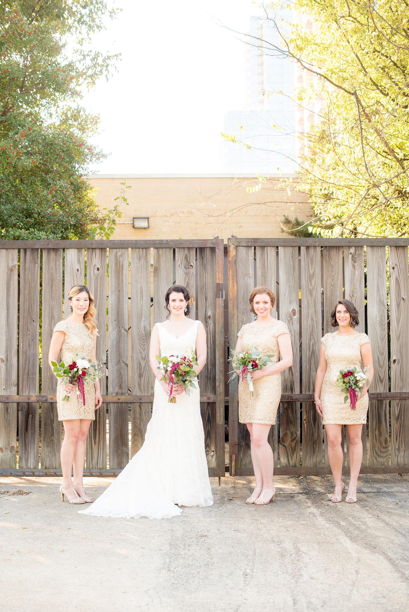 Mikkel Paige Photography photos of a wedding in downtown Raleigh. An image of the bridesmaids in short gold dresses with fall bouquets.