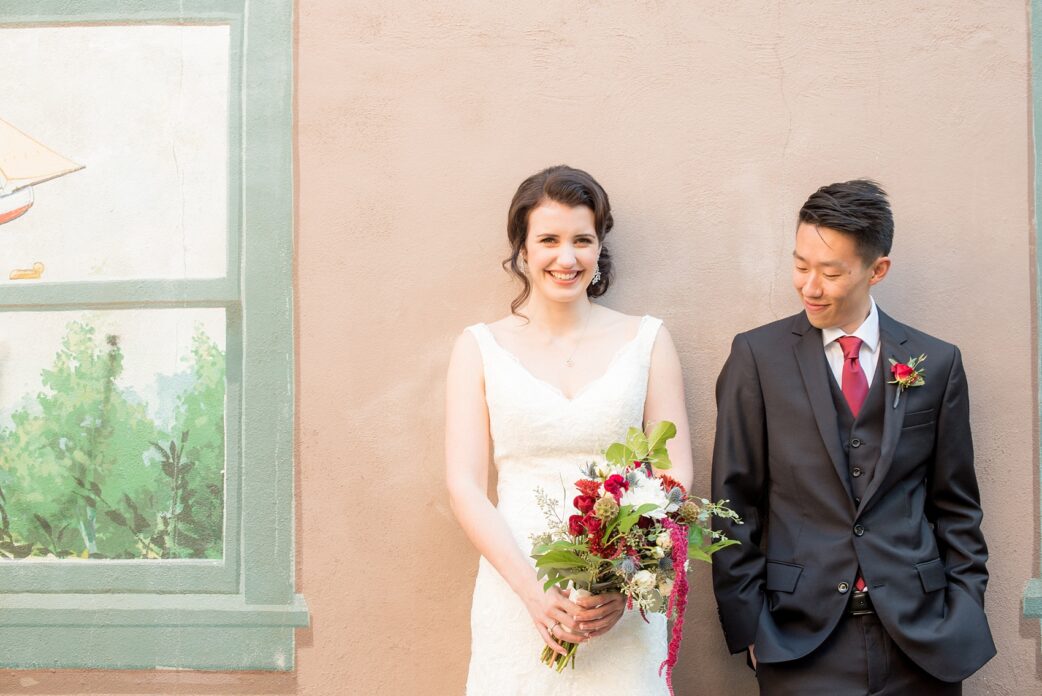 Mikkel Paige Photography photos of a wedding in downtown Raleigh. An image of the bride and groom in front of street art with a fall colors bouquet.