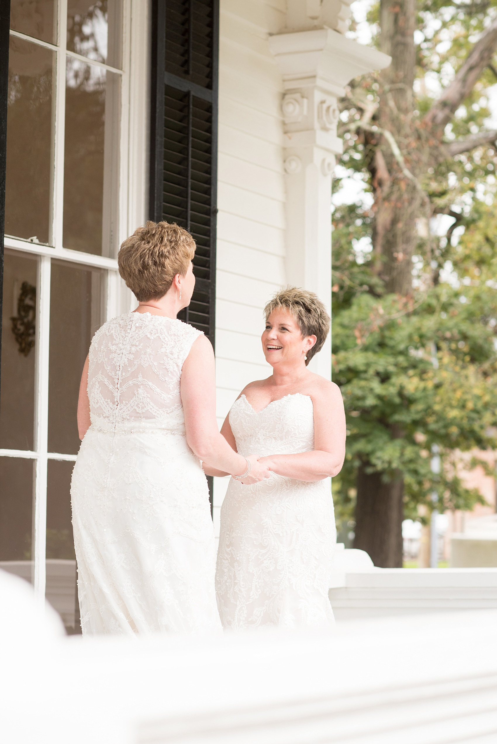 Mikkel Paige Photography photos from a Merrimon-Wynne House wedding in Raleigh. Two brides tie the knot during their same-sex fall wedding. Pictures on the porch of the beautiful southern mansion venue.