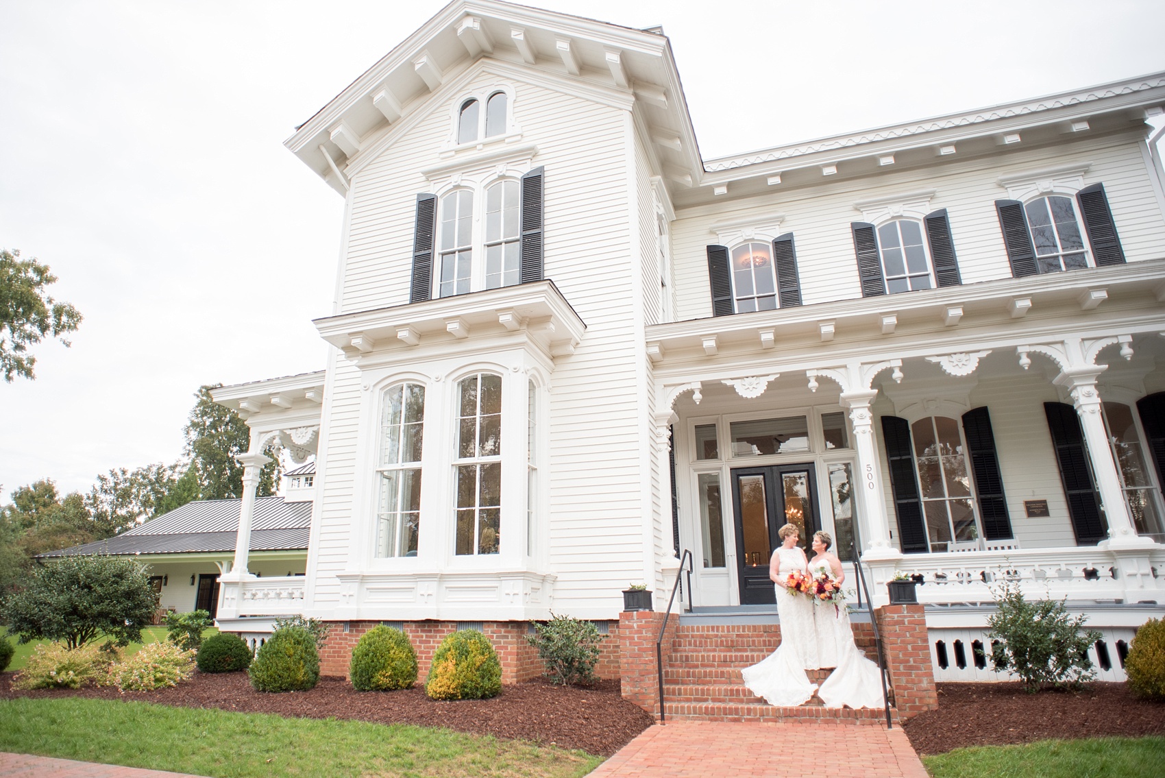 Mikkel Paige Photography photos from a Merrimon-Wynne House wedding in Raleigh. Two brides tie the knot during their same-sex fall wedding. Pictures on the porch of the beautiful southern mansion venue.