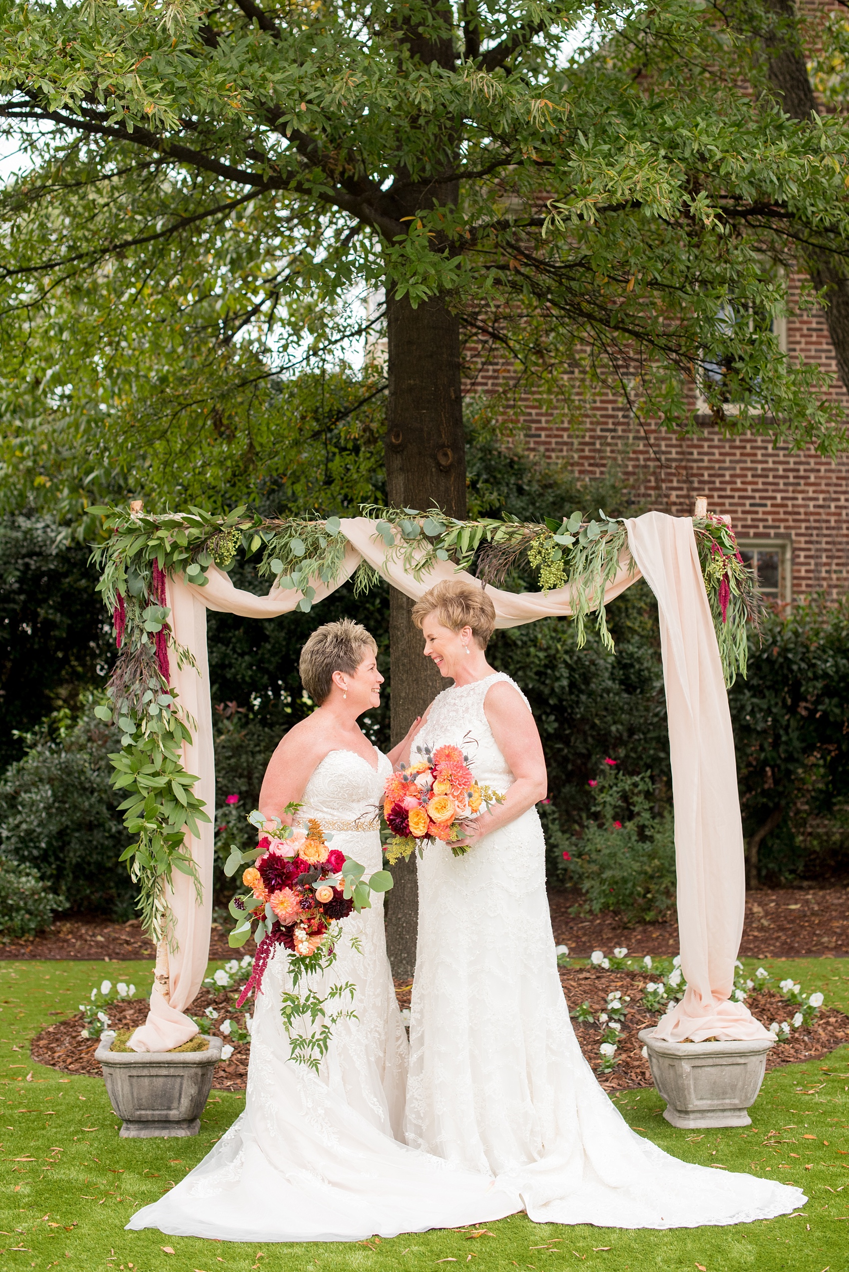 Mikkel Paige Photography photos from a Merrimon-Wynne House wedding in Raleigh. Two brides in front of their floral ceremony arbor for a same-sex, lesbian wedding.
