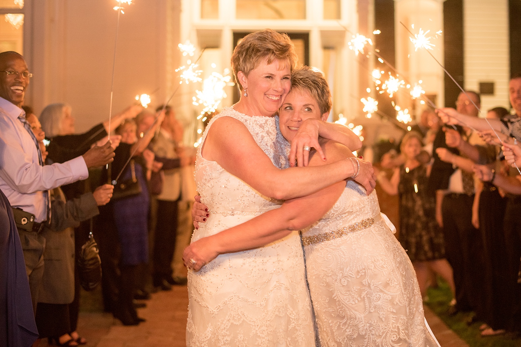 Mikkel Paige Photography photos from a Merrimon-Wynne House wedding in Raleigh. The brides embrace during a beautiful sparkler exit in front of their southern mansion venue.