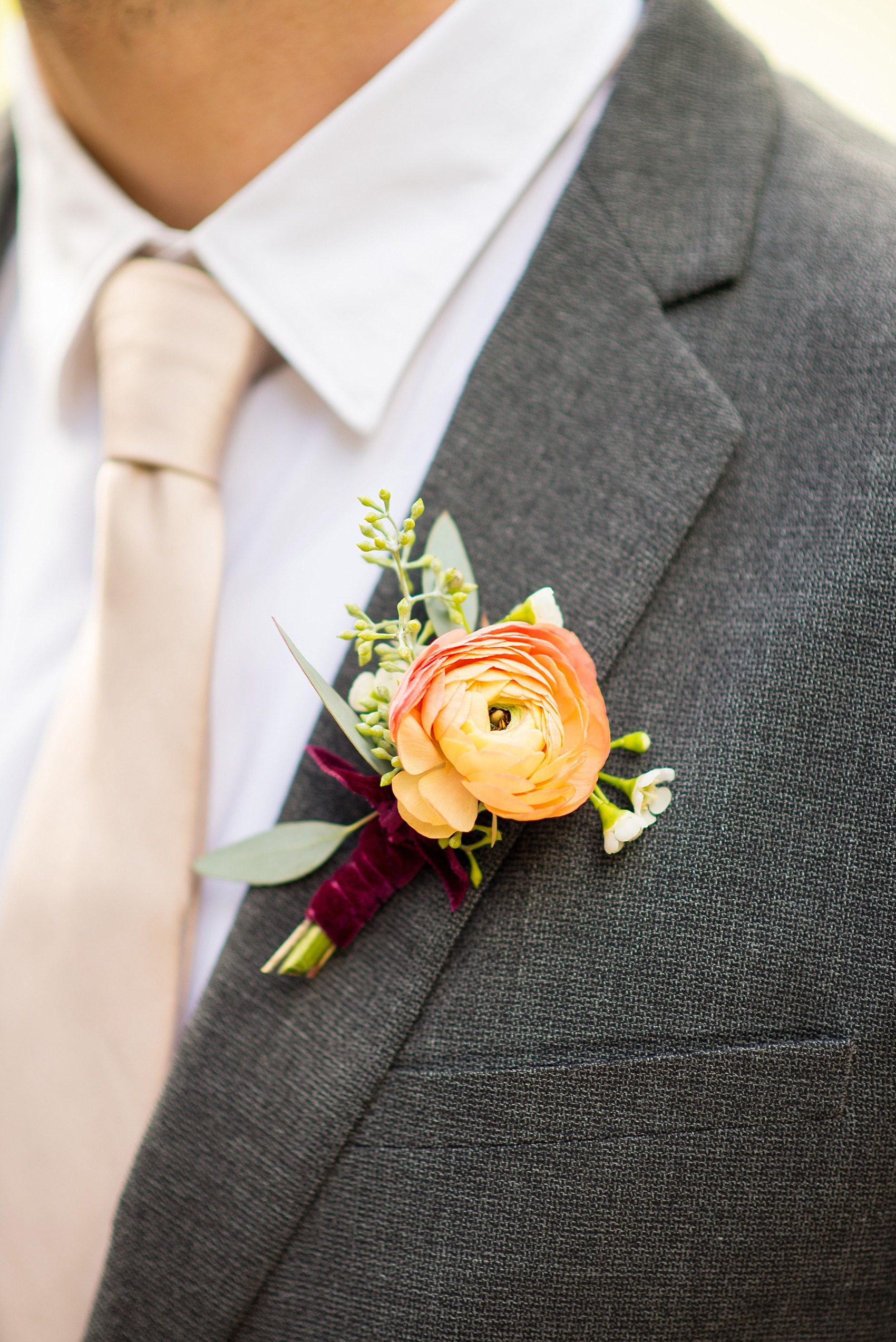 Mikkel Paige Photography photo of an orange ranunculus boutonniere by Sachi Rose for a Prospect Park Boathouse wedding in Brooklyn, New York.