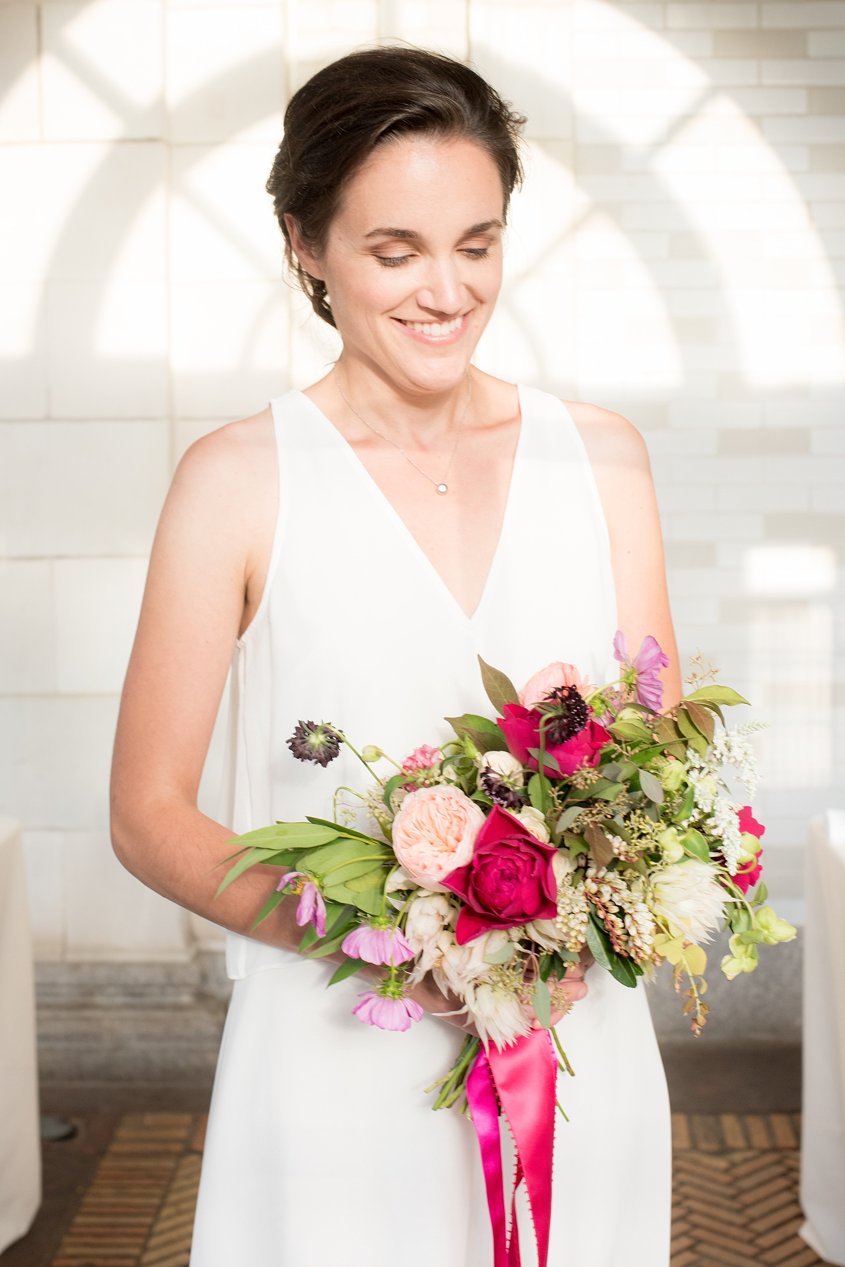 Mikkel Paige Photography photo of an all-white dressed bridesmaid holding a pink and blush bouquet for a wedding at Prospect Park Boathouse in Brooklyn, NY. Flowers by Sachi Rose.