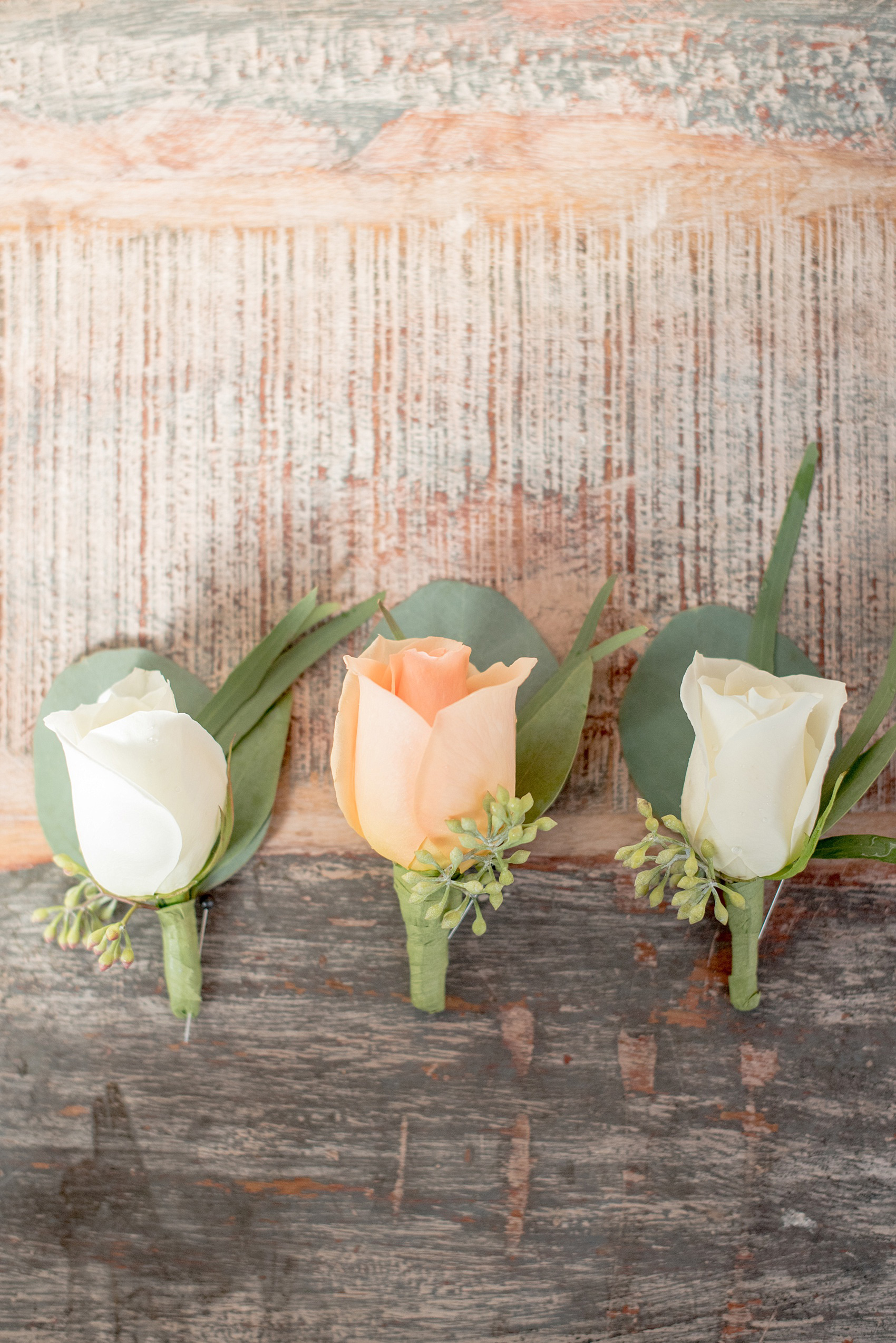 Mikkel Paige Photography photo of peach and white rose boutonnieres with eucalyptus for a wedding at The Rickhouse, Durham.