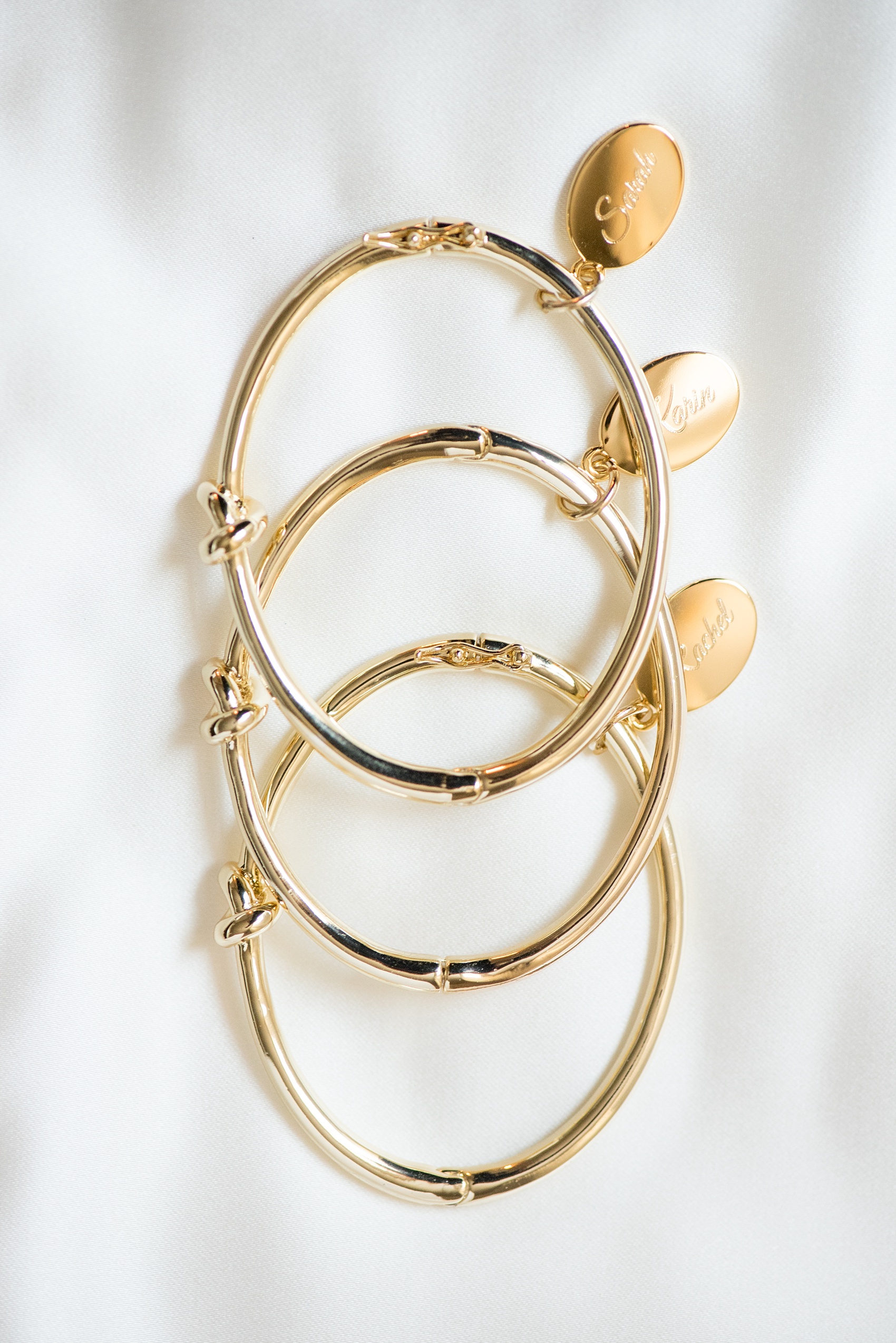 Mikkel Paige Photography detail photo of bridesmaids gifts: gold "tie the knot" bracelets with their names on charms.