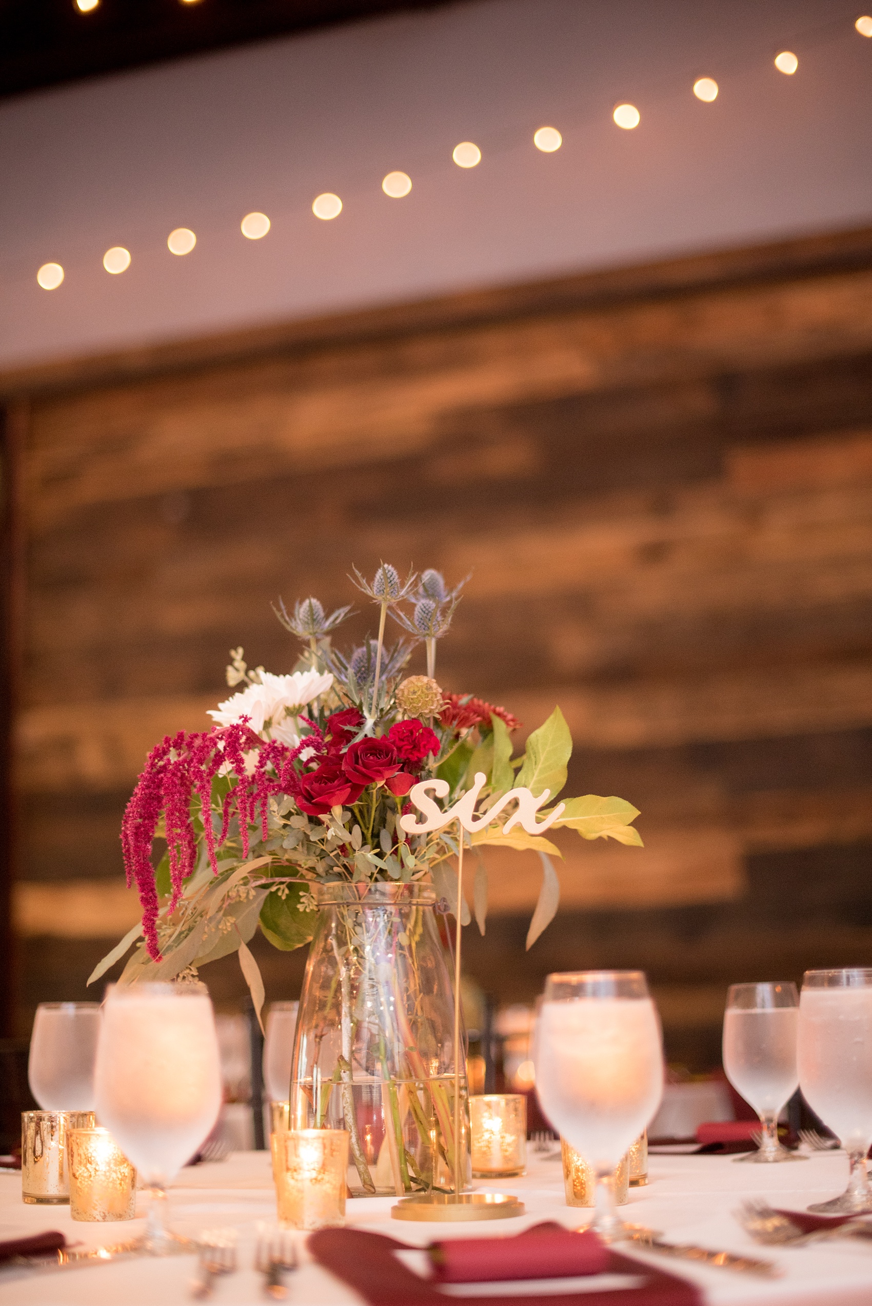 Mikkel Paige Photography photos from a wedding at 214 Martin Street in downtown Raleigh with fall flowers and bistro market lights. Gold painted script wood words served as table numbers.