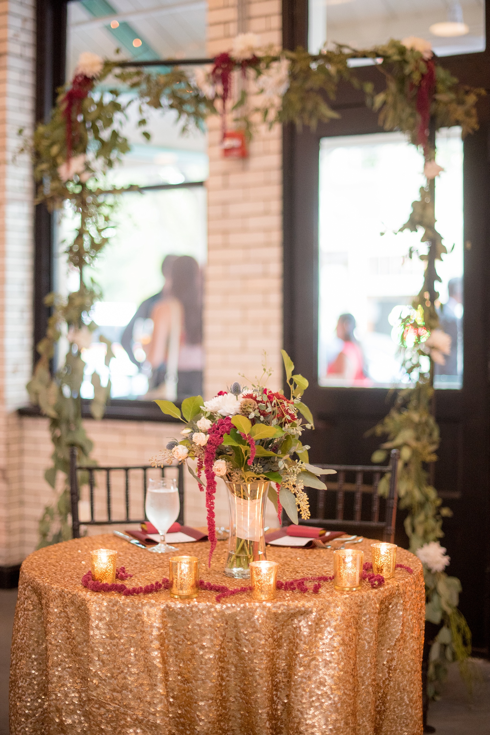 Mikkel Paige Photography photos from a wedding at 214 Martin Street in downtown Raleigh with burgundy and white fall flowers on gold sequin tablecloths with bistro market lights.