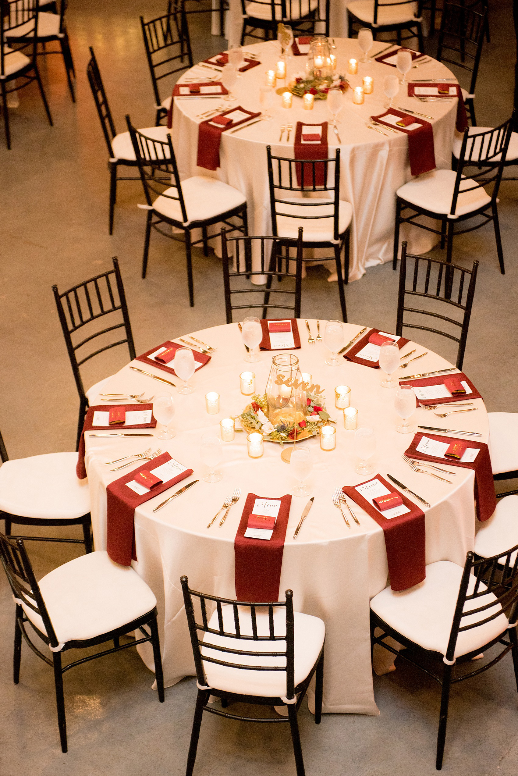 Mikkel Paige Photography photos from a wedding at 214 Martin Street in downtown Raleigh with burgundy and white fall flowers and bistro market lights. Gold painted script wood words served as table numbers.