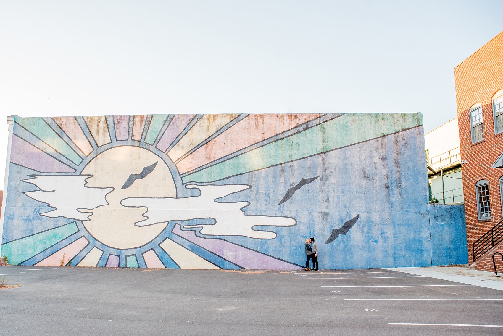 Mikkel Paige Photography photos of a Durham engagement session in downtown Durham against a colorful sun mural.