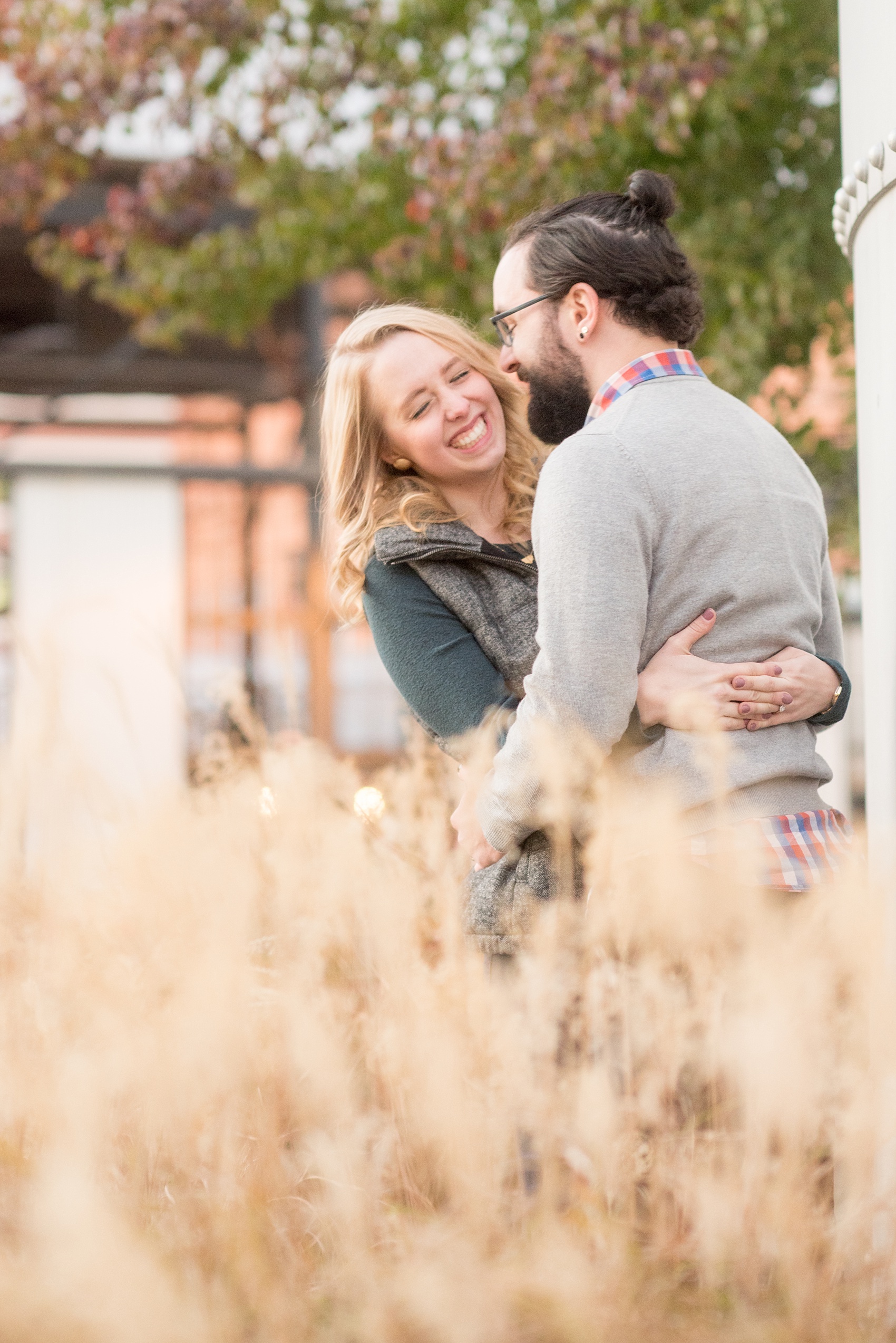 Mikkel Paige Photography photos of a Durham engagement session in downtown Durham. The bride and groom got cozy at American Tobacco Campus in this picture amongst the grasses.